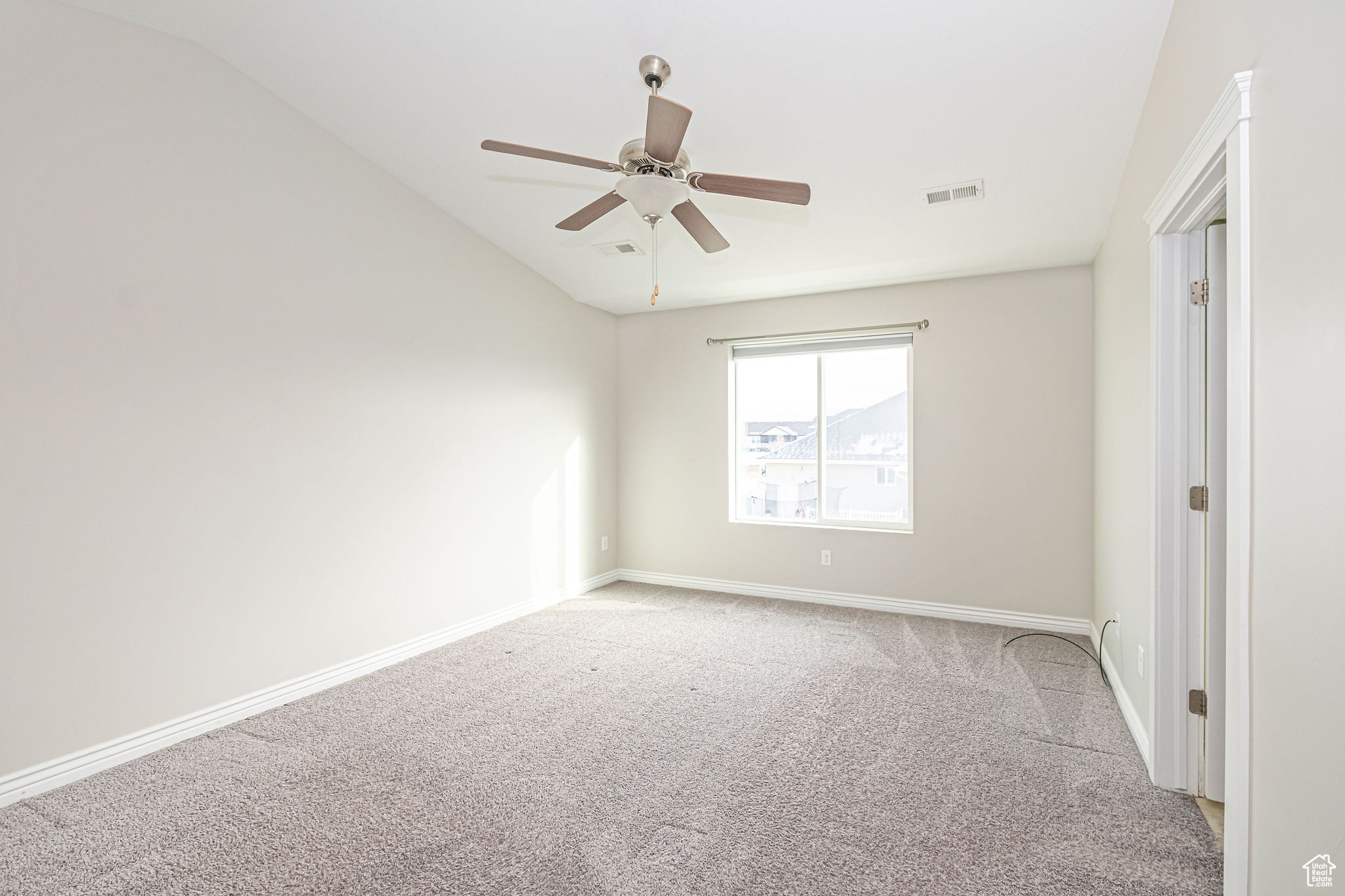 Spare room featuring ceiling fan, light colored carpet, and lofted ceiling