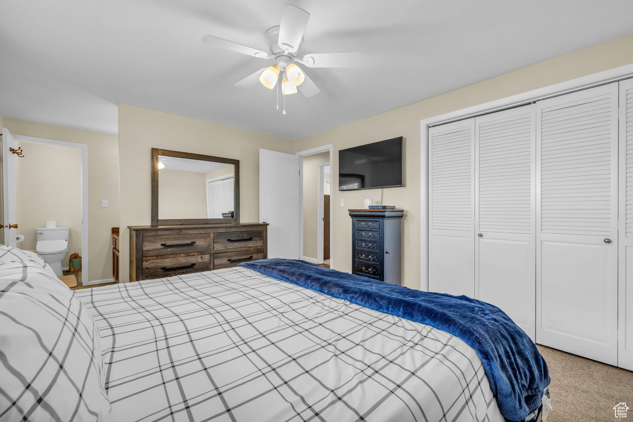 Bedroom with carpet flooring, a closet, ceiling fan, and ensuite bath