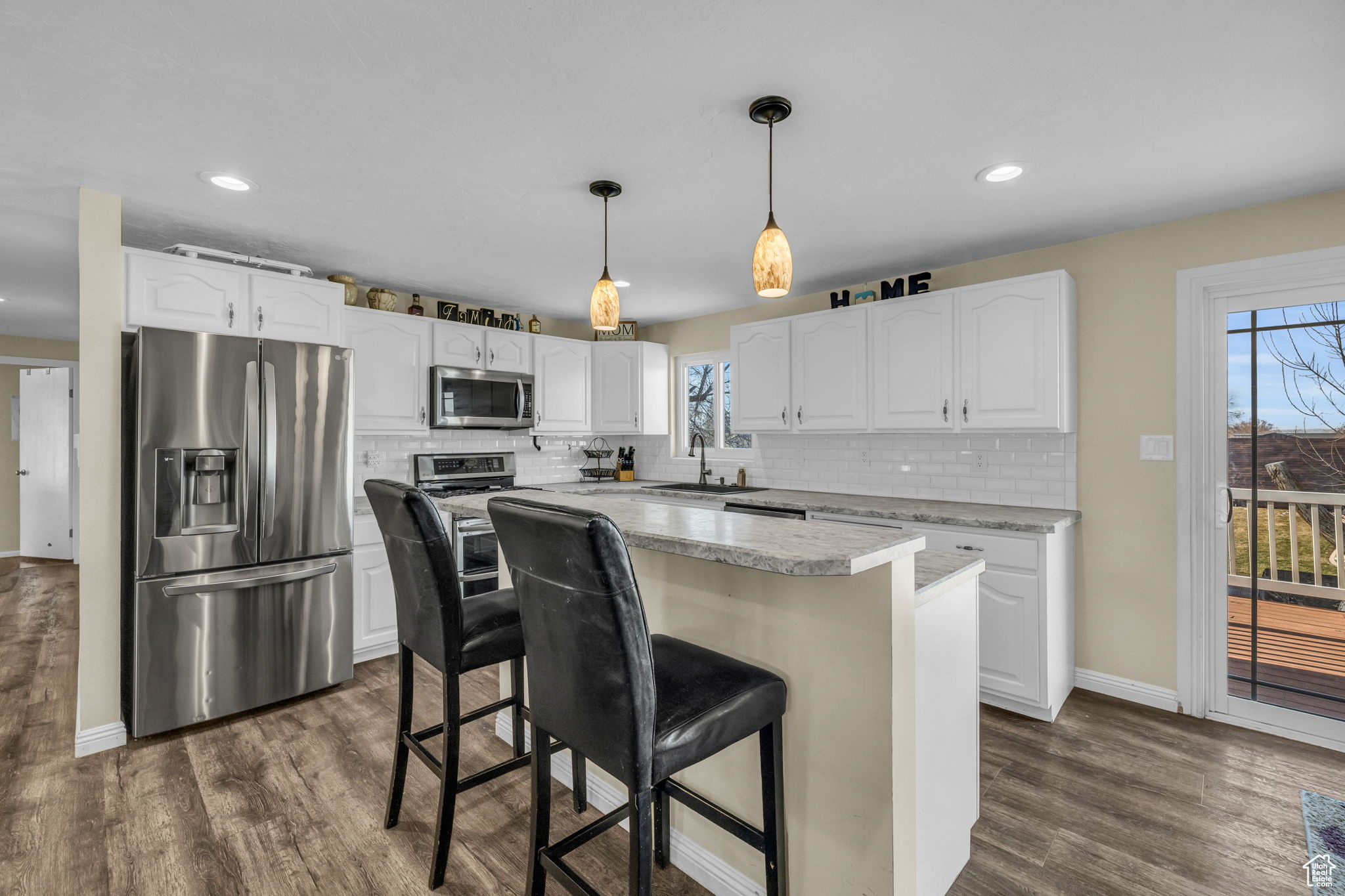 Kitchen featuring stainless steel appliances, a breakfast bar area, a center island, and white cabinetry