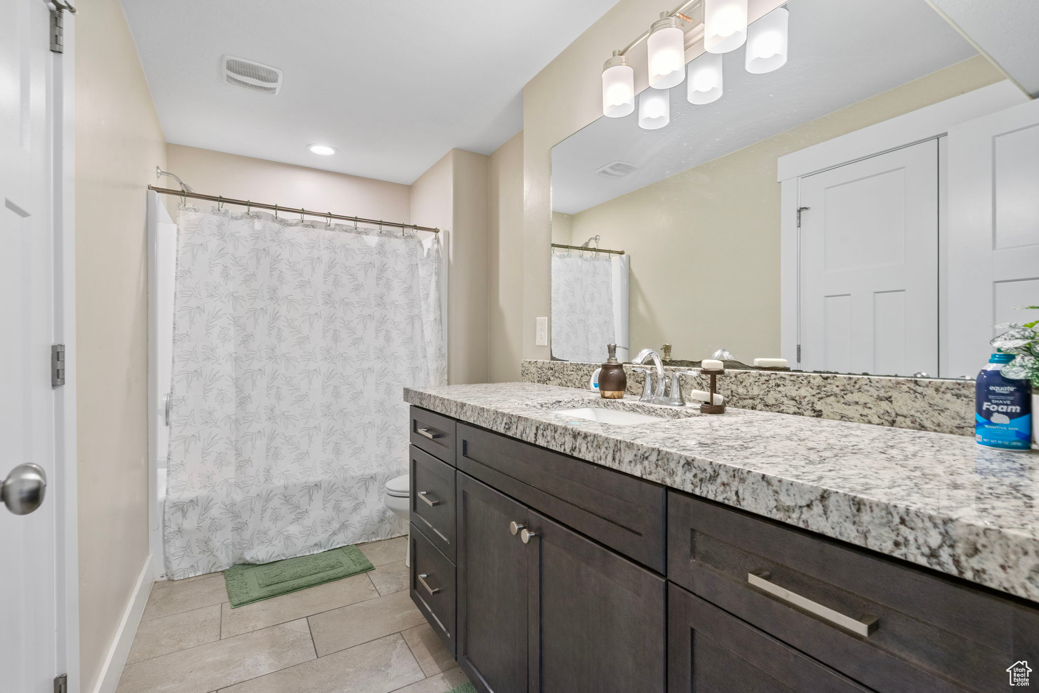 Bathroom featuring a shower with curtain, tile patterned flooring, vanity, and toilet