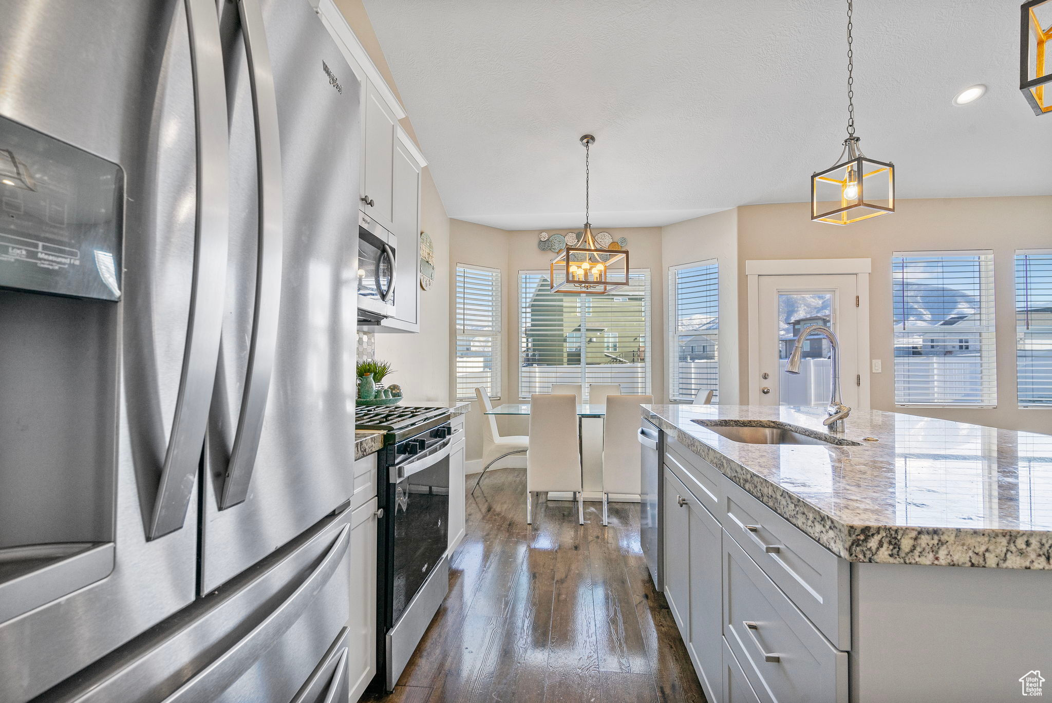 Kitchen with sink, pendant lighting, an island with sink, and appliances with stainless steel finishes