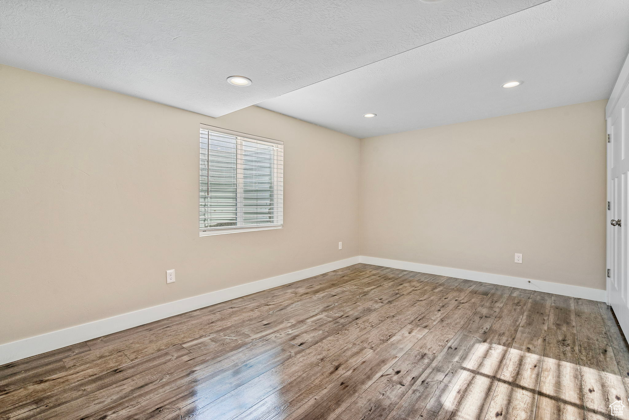 Empty room featuring wood-type flooring and a textured ceiling