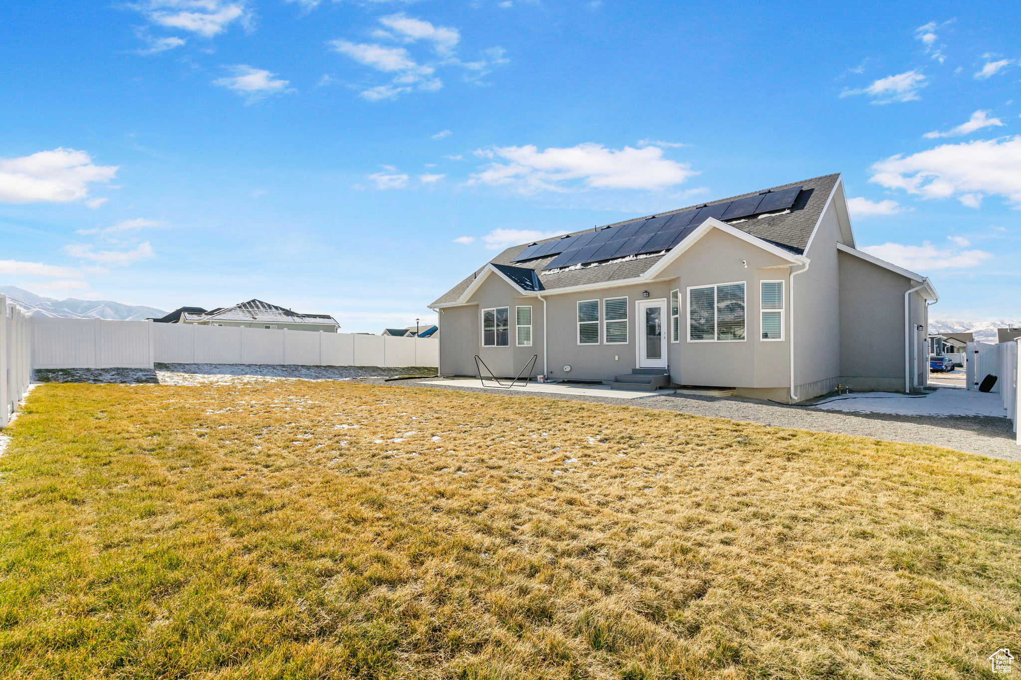 Back of house with solar panels, a patio, and a lawn