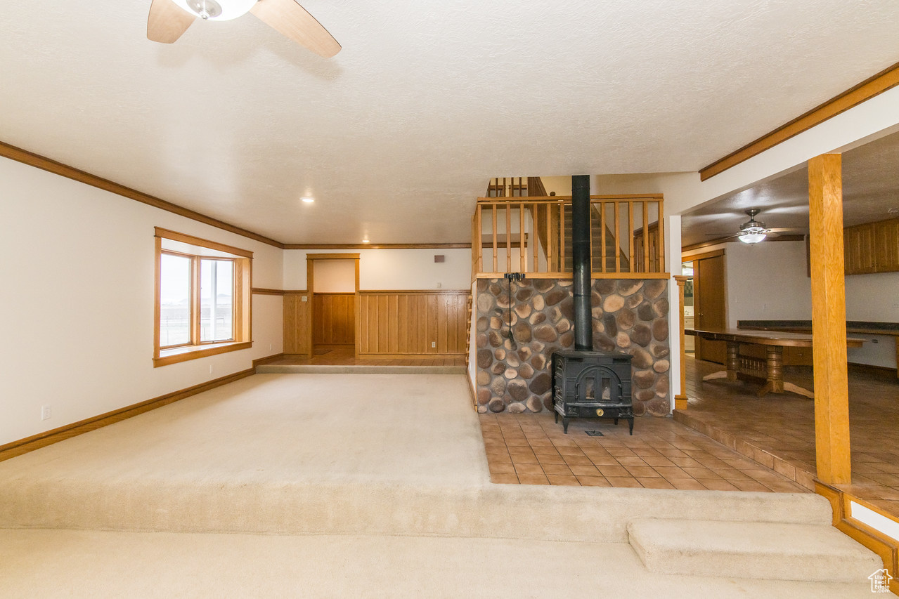 Living room featuring oak molding, light colored carpet, and a wood stove