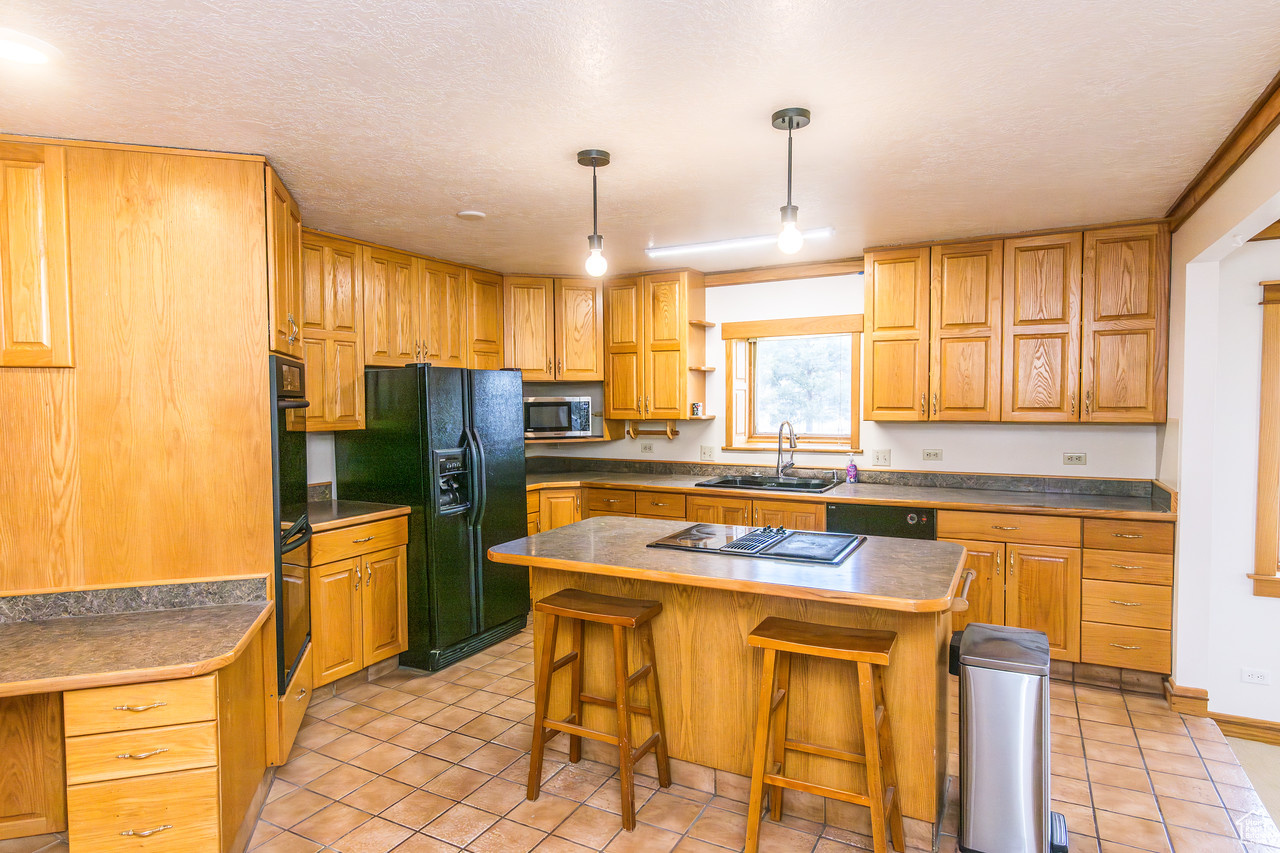 Kitchen featuring pendant lighting, a center island, black appliances, a kitchen breakfast bar,