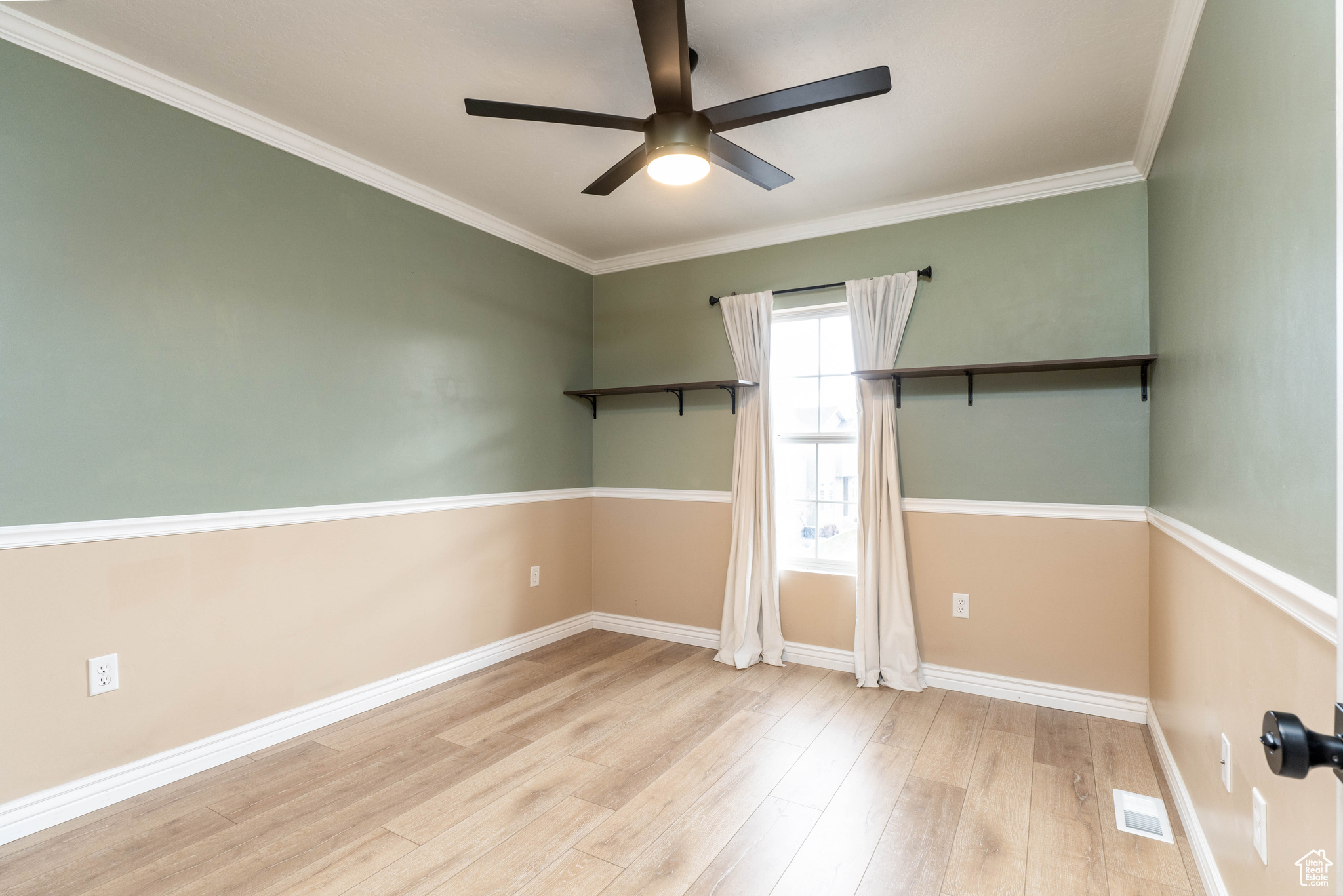 Empty room with ceiling fan, crown molding, and light wood-type flooring