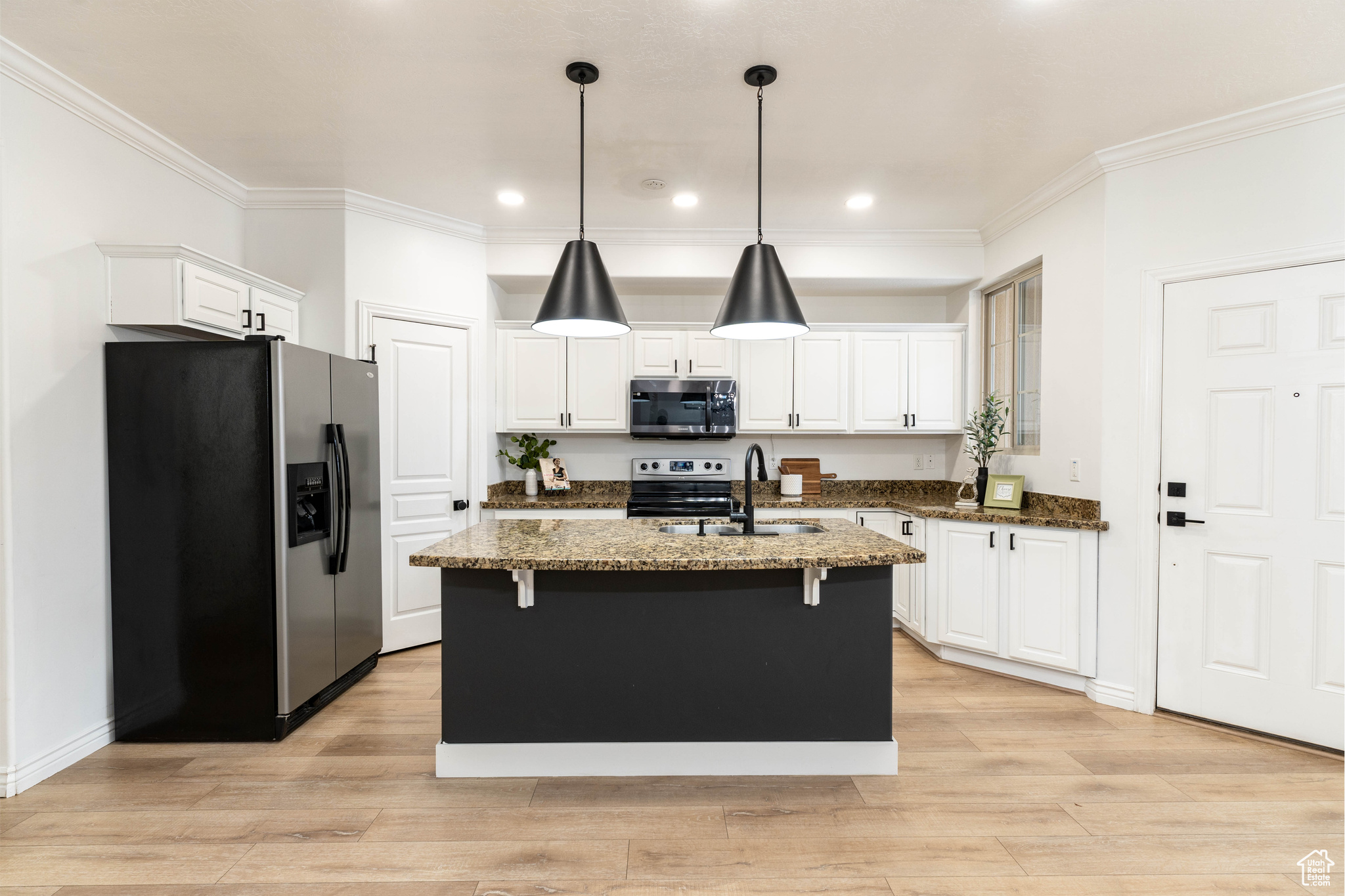 Kitchen featuring sink, stainless steel appliances, dark stone countertops, and a center island with sink