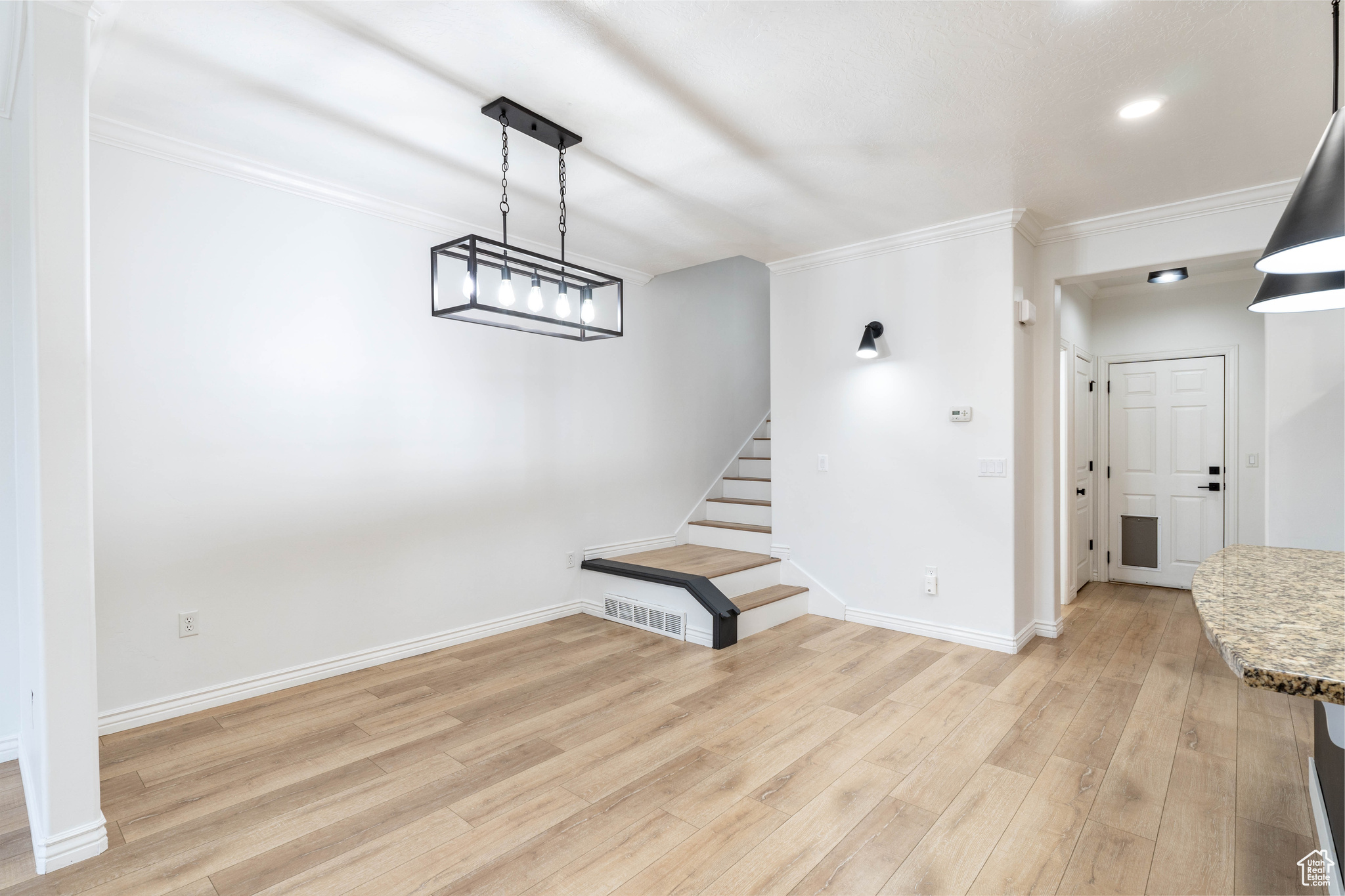 Unfurnished living room with light wood-type flooring and crown molding