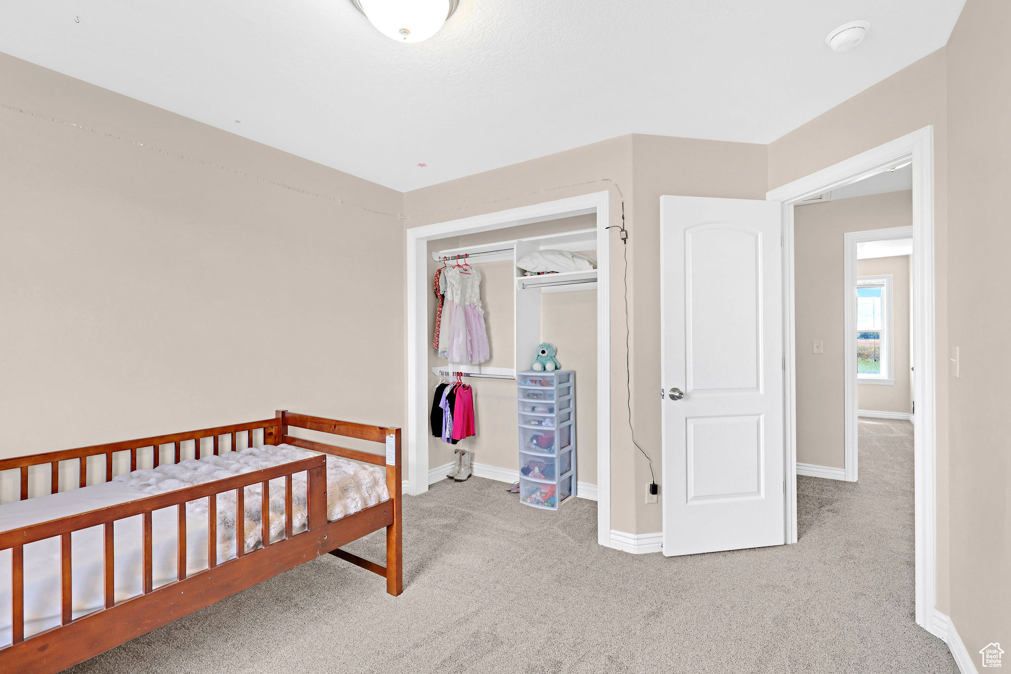 Bedroom with a closet, a crib, and light carpet