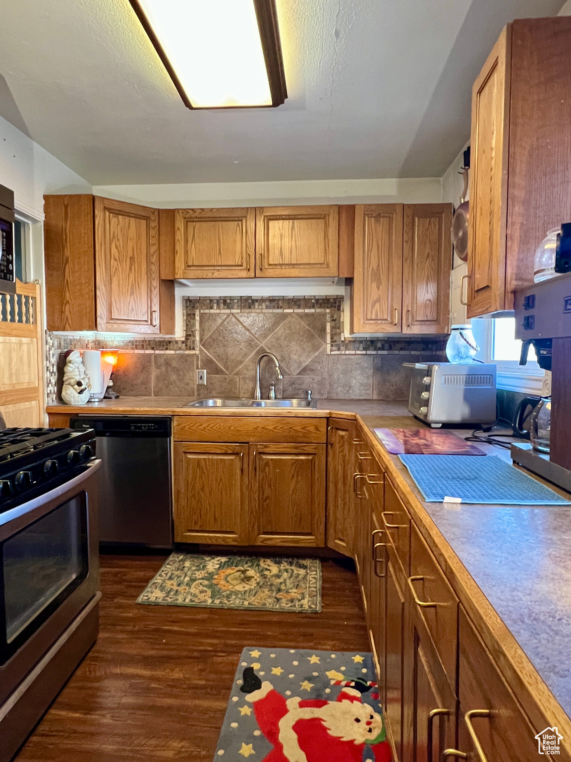 Kitchen featuring sink, decorative backsplash, dark wood-type flooring, and appliances with stainless steel finishes