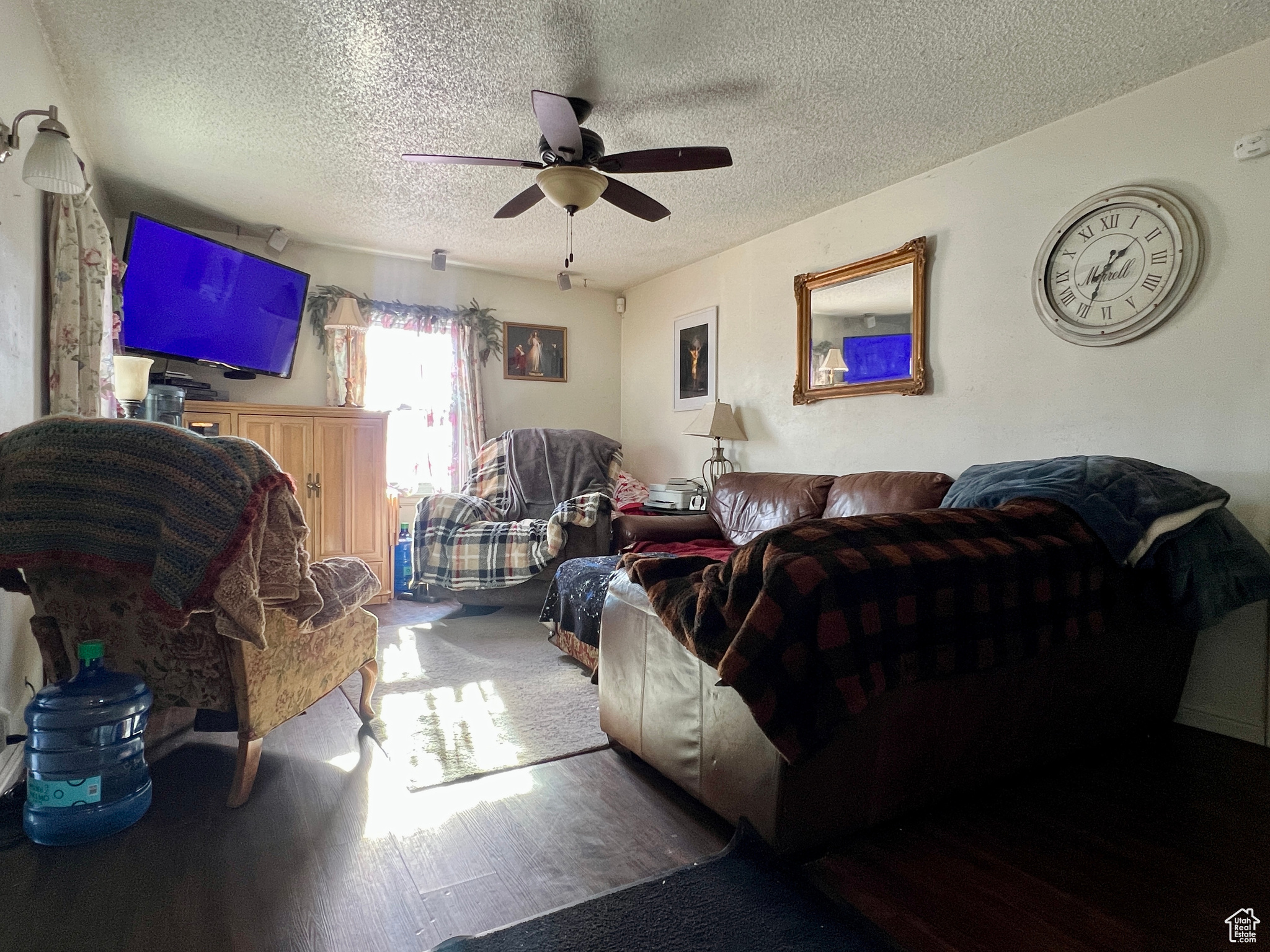 Living room with a textured ceiling, ceiling fan, and hardwood / wood-style floors