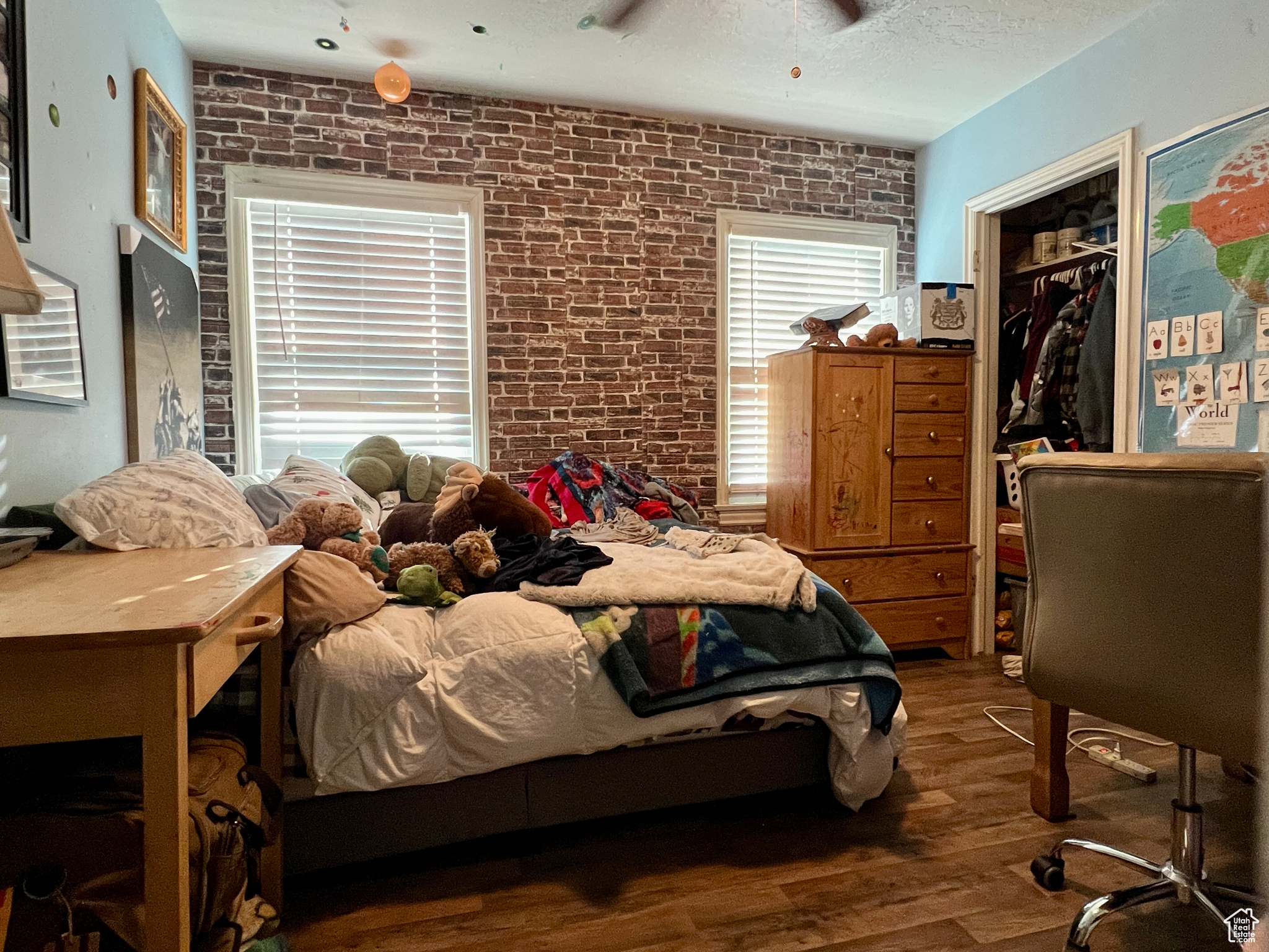 Bedroom with brick wall, wood-type flooring, a closet, and ceiling fan