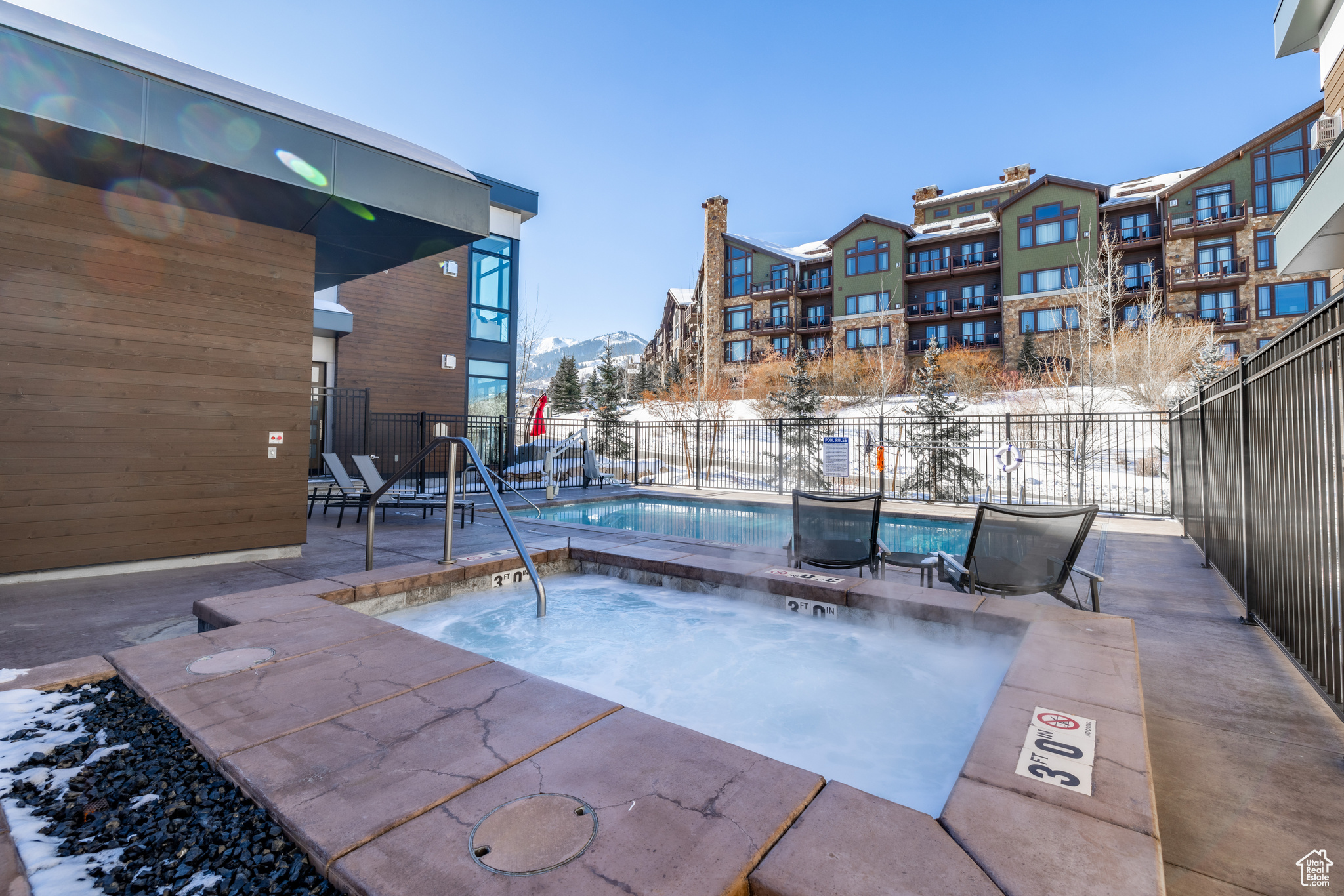 Snow covered pool with a hot tub and a mountain view