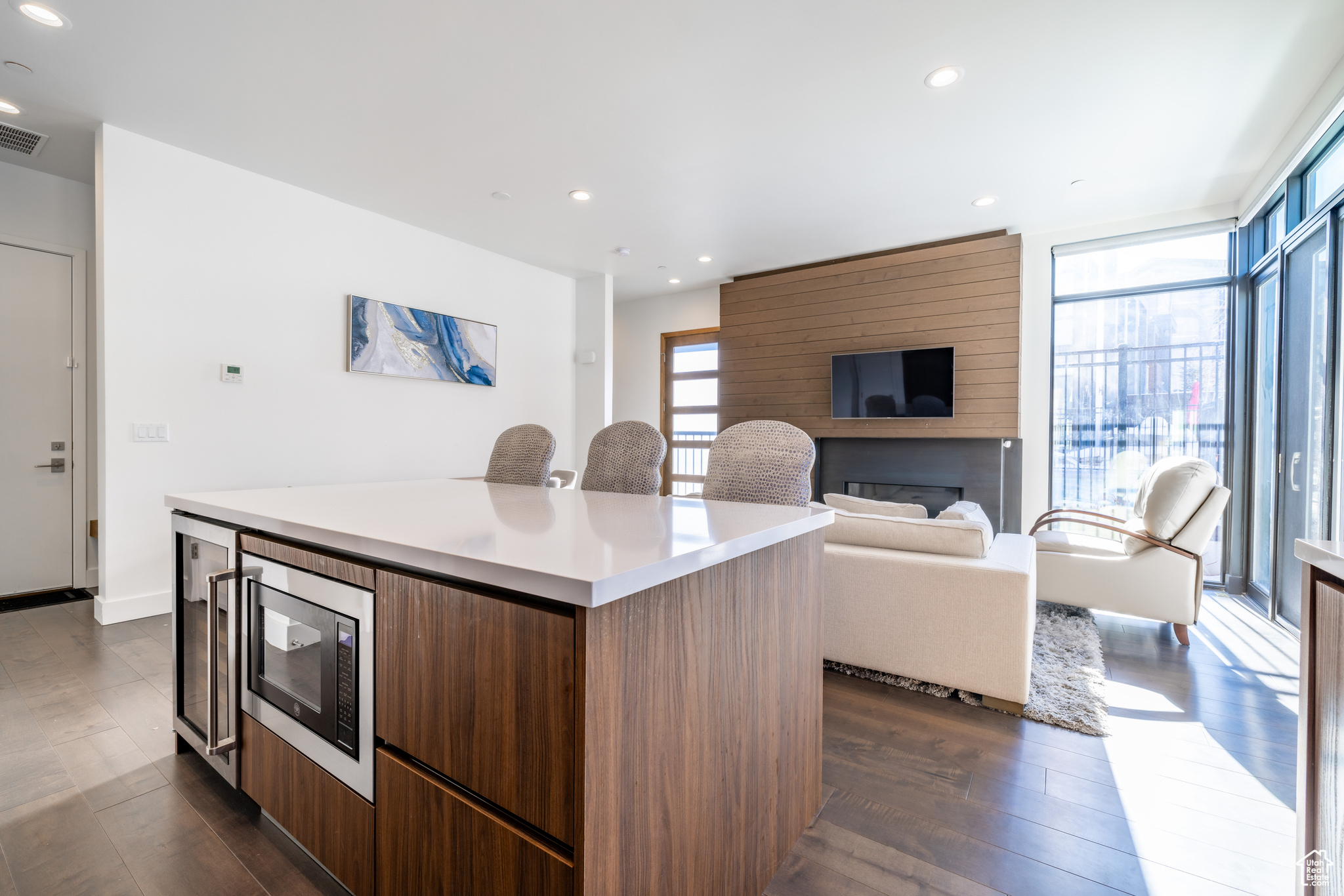 Kitchen with a fireplace, dark hardwood / wood-style floors, a kitchen island, stainless steel microwave, and floor to ceiling windows