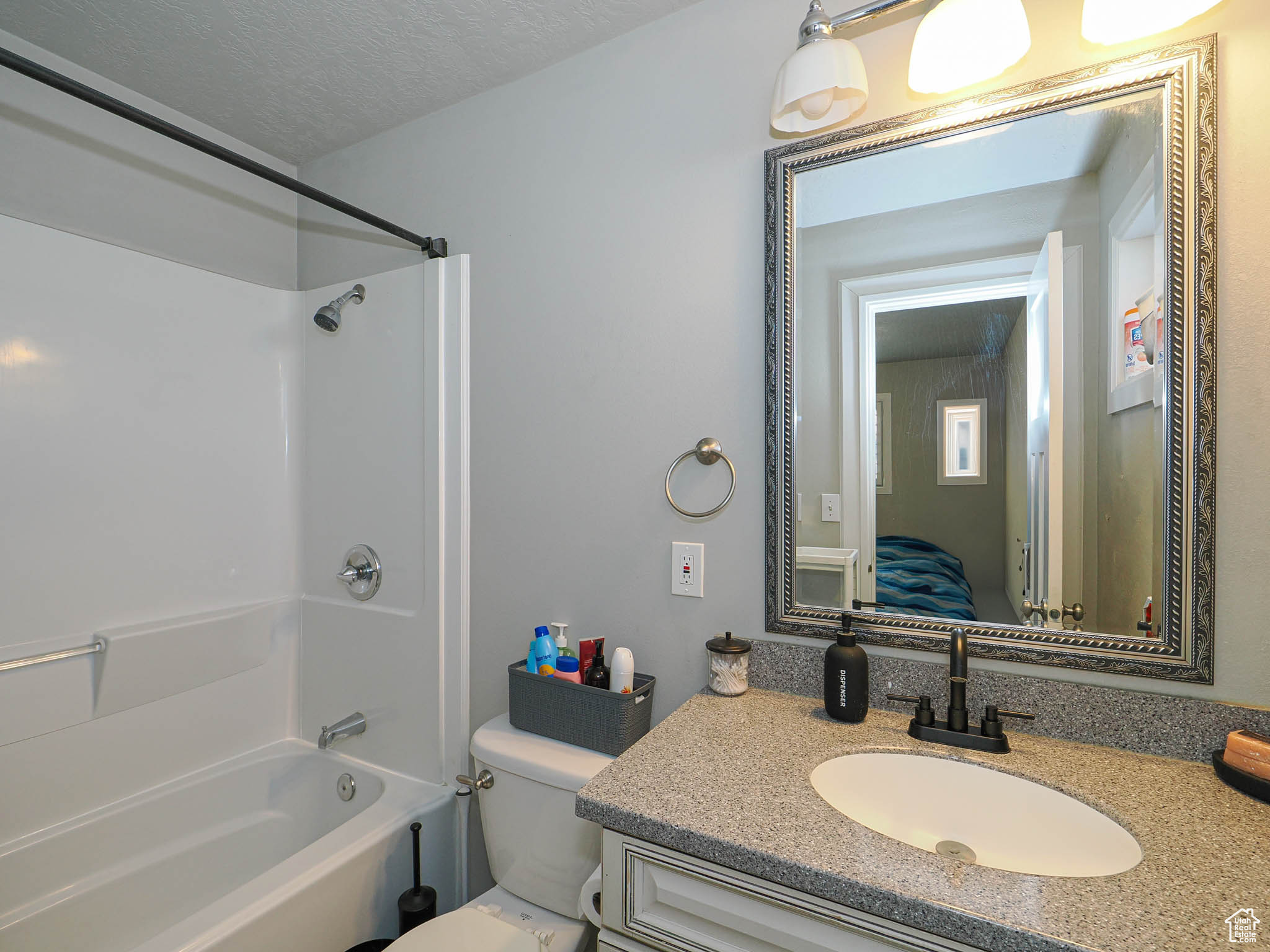 Full bathroom with a textured ceiling, shower / washtub combination, vanity, and toilet