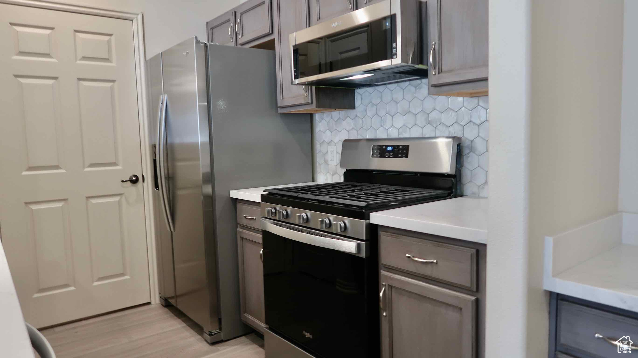 Kitchen with appliances with stainless steel finishes, light wood-type flooring, and tasteful backsplash