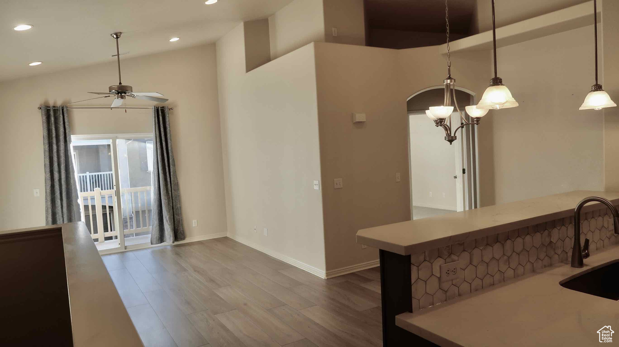 Interior space with a high ceiling, ceiling fan with notable chandelier, sink, decorative light fixtures, and hardwood / wood-style floors