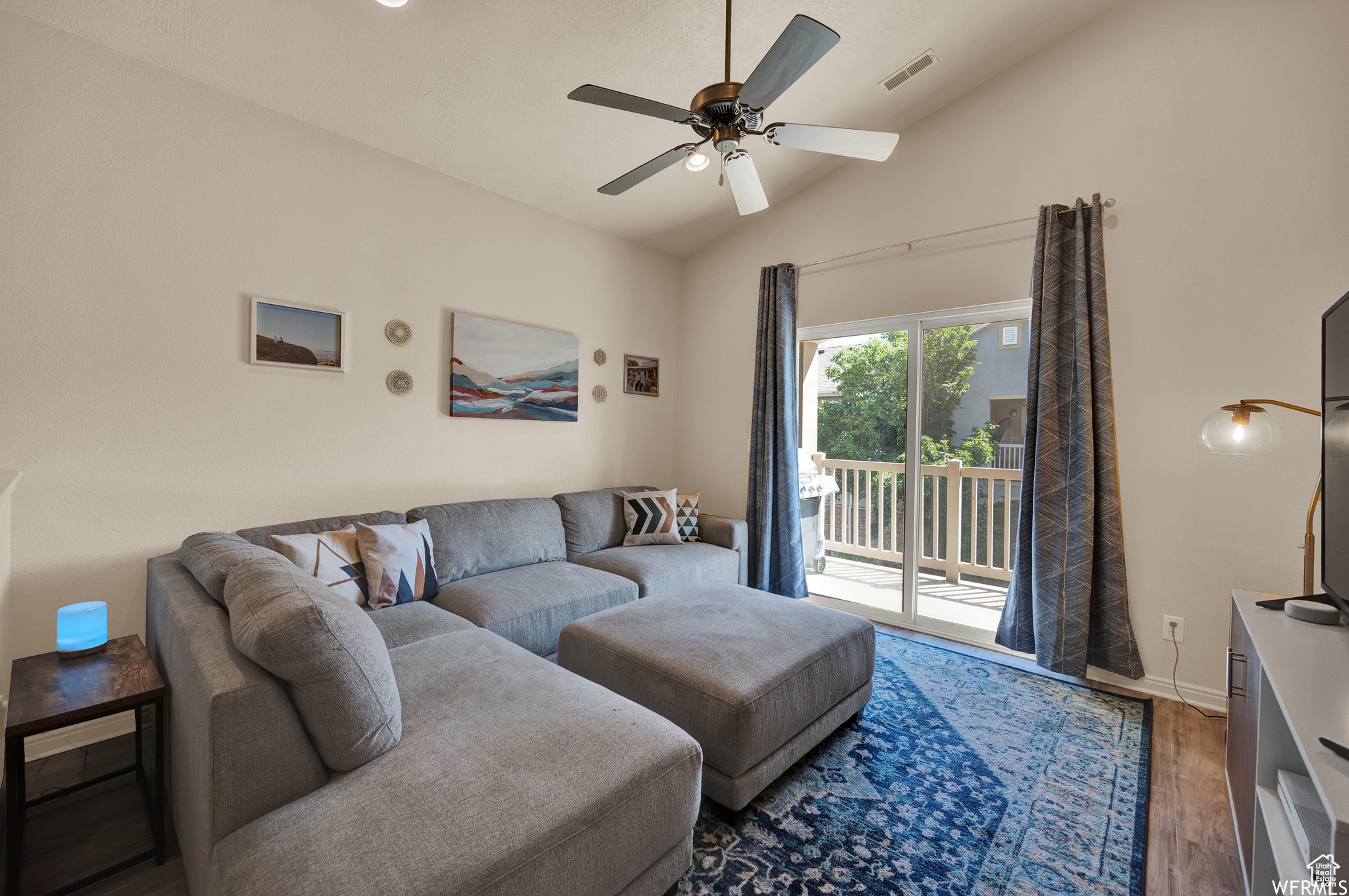 Living room with ceiling fan, lofted ceiling, and dark wood-type flooring