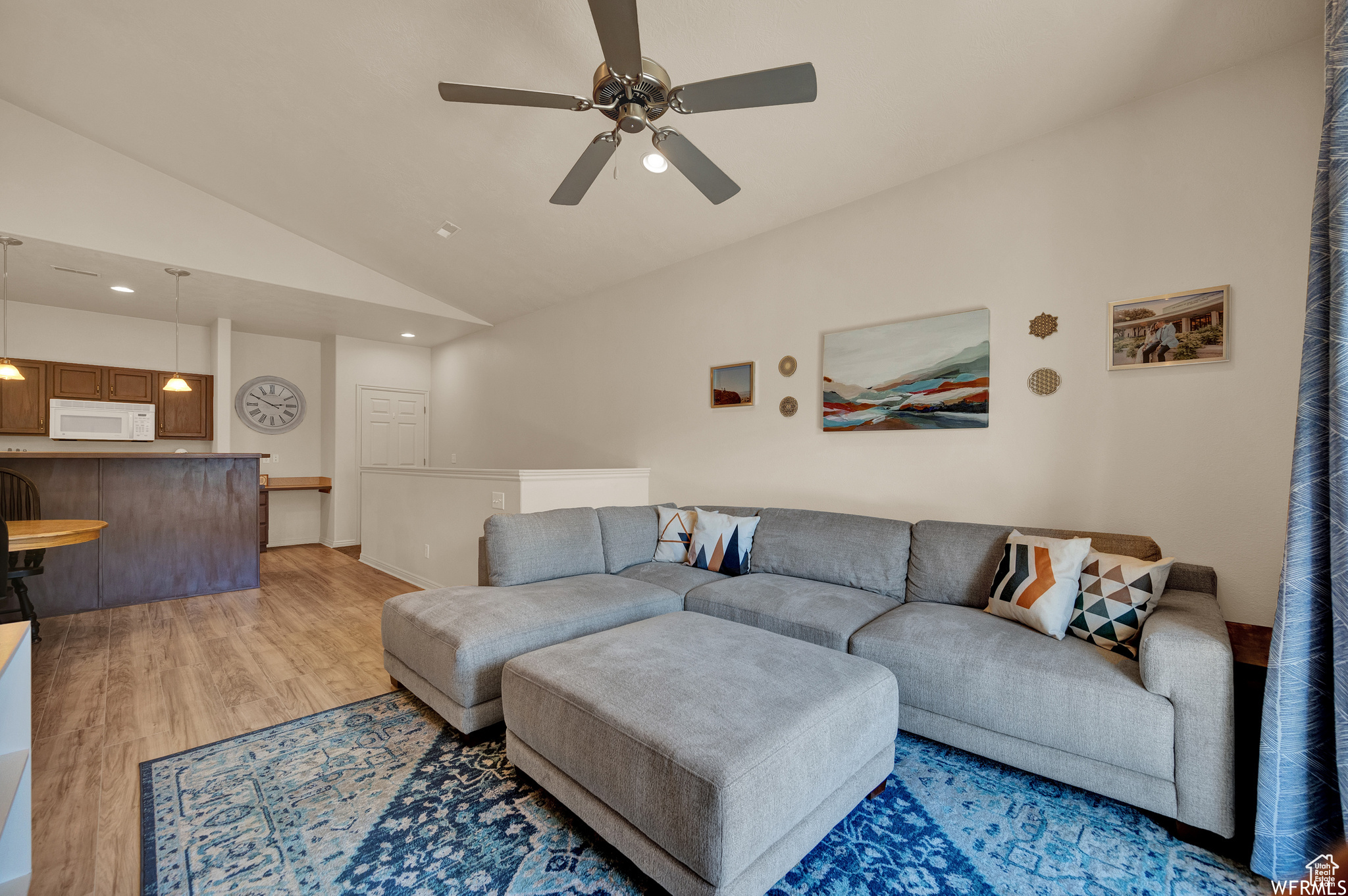 Living room with ceiling fan, light hardwood / wood-style flooring, and high vaulted ceiling