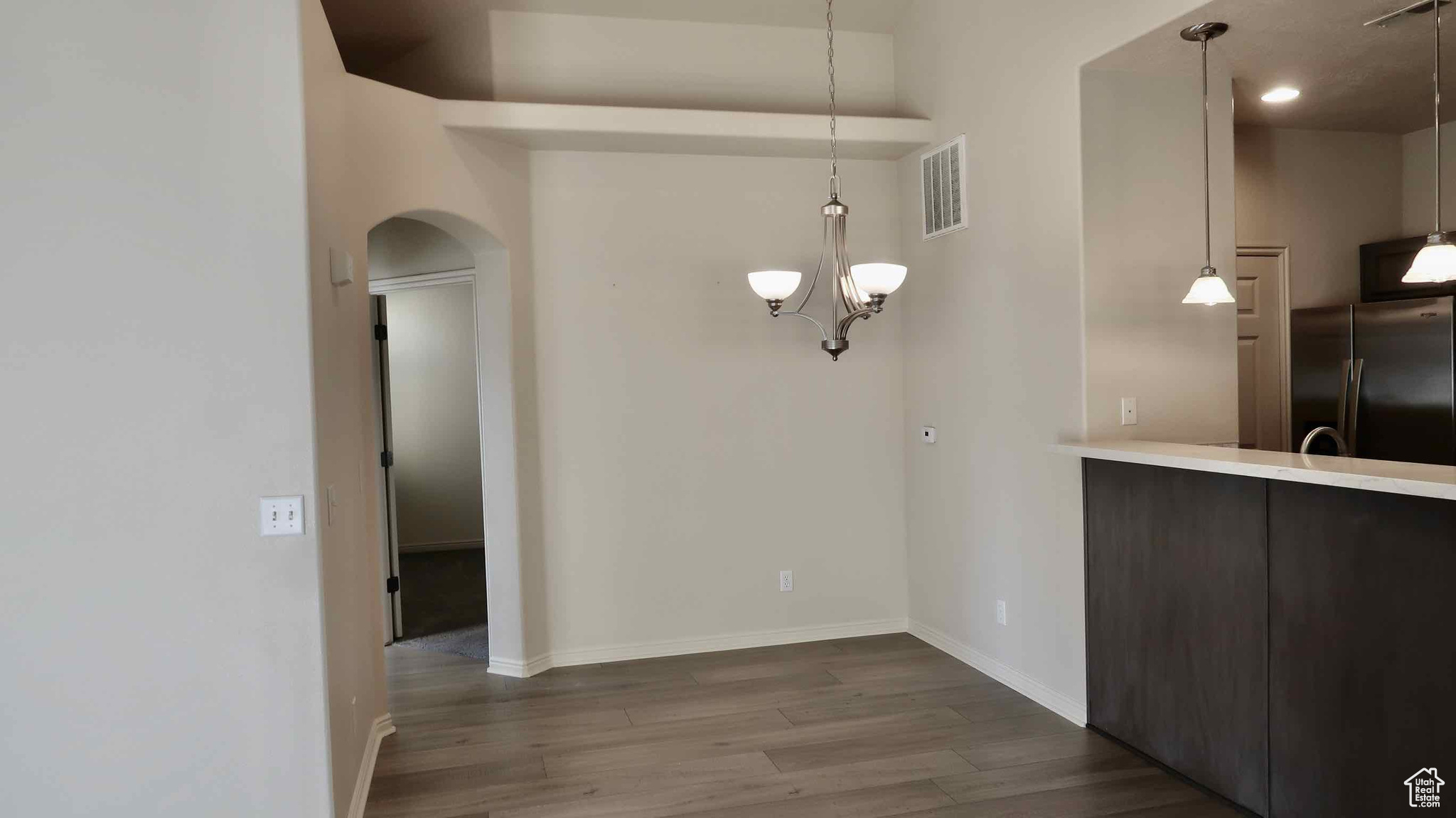 Unfurnished dining area with wood-type flooring and a notable chandelier