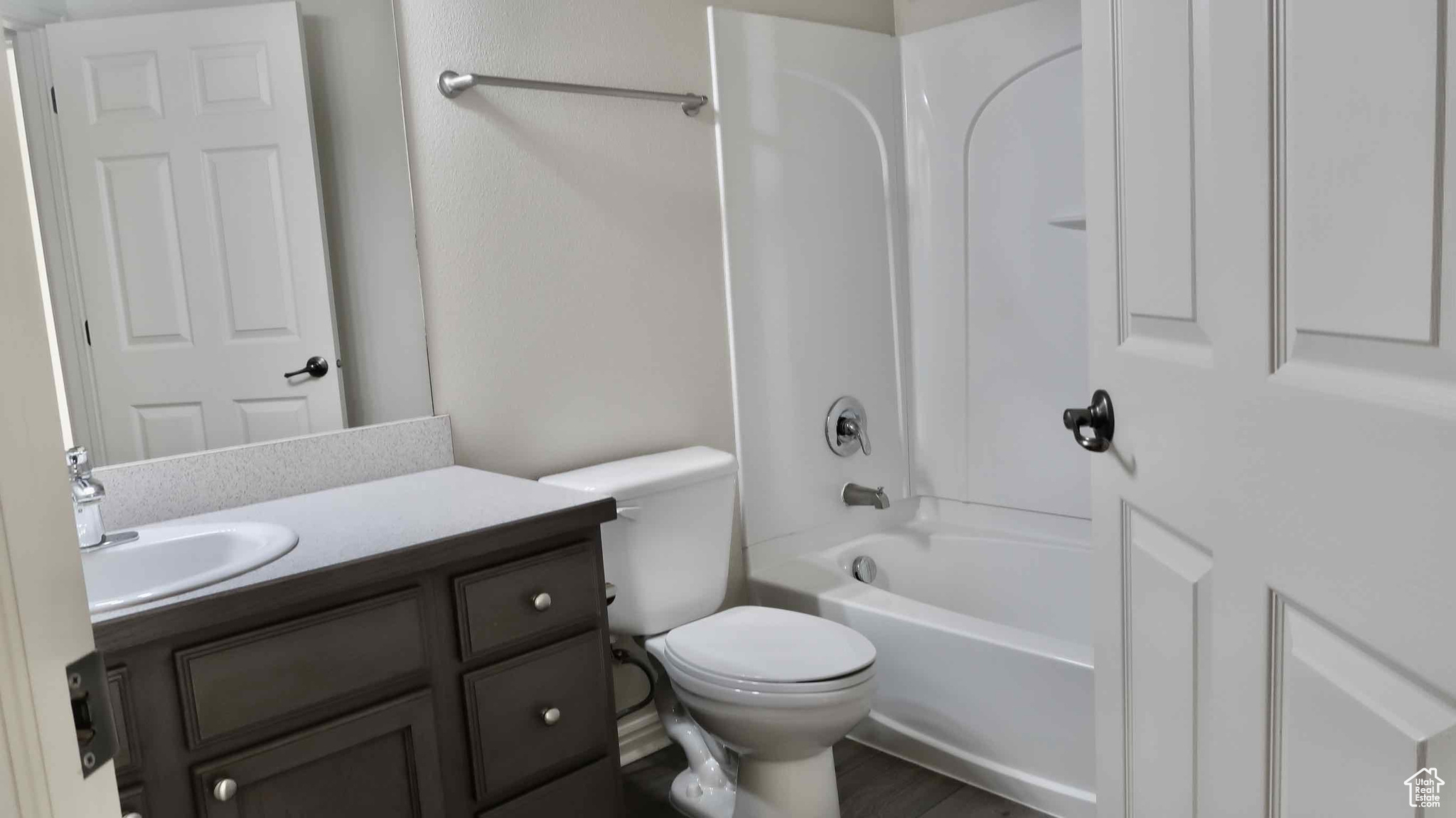 Full bathroom featuring wood-type flooring, vanity, shower / bath combination, and toilet