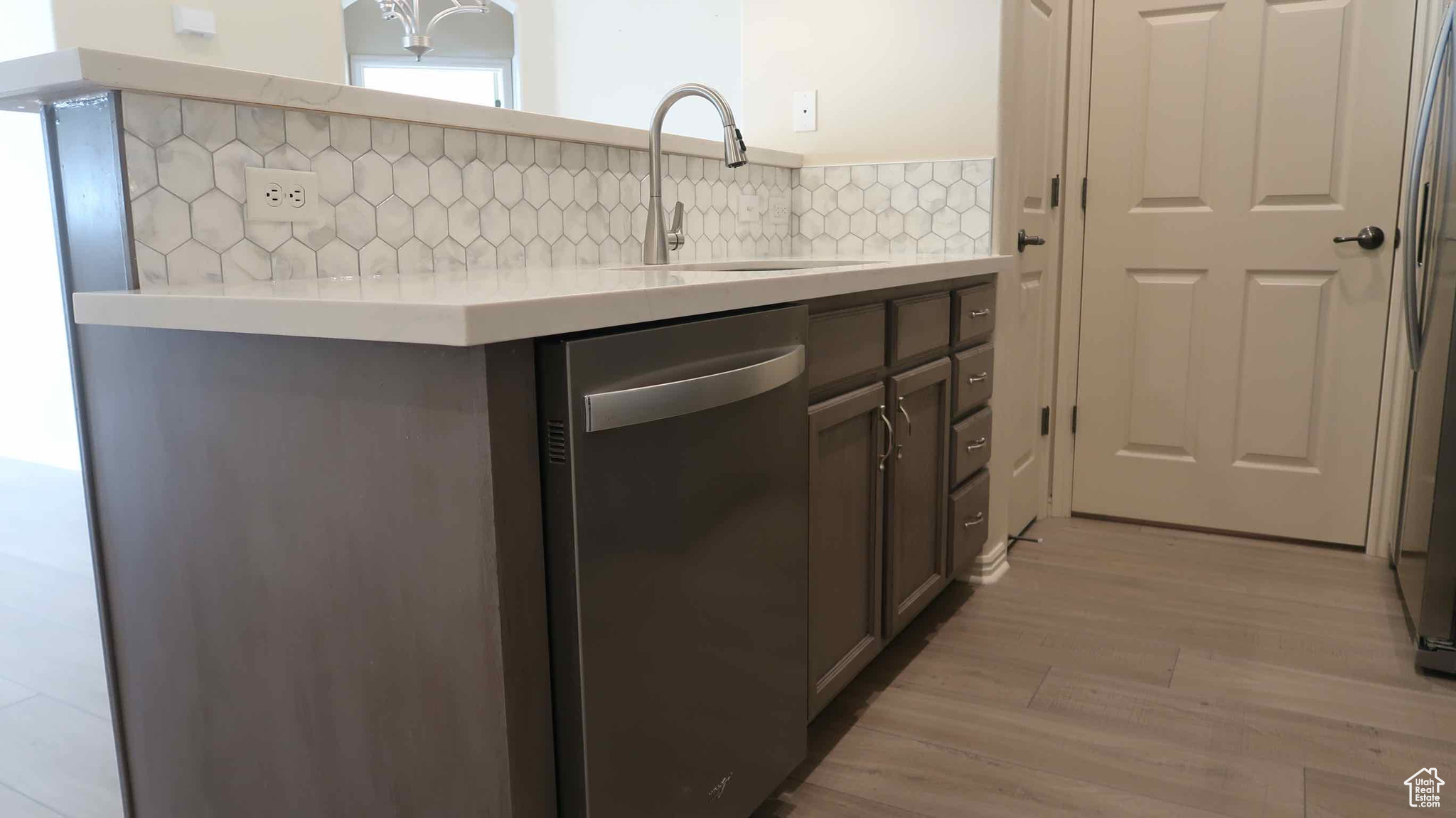 Kitchen featuring dishwasher, light hardwood / wood-style floors, decorative backsplash, and sink