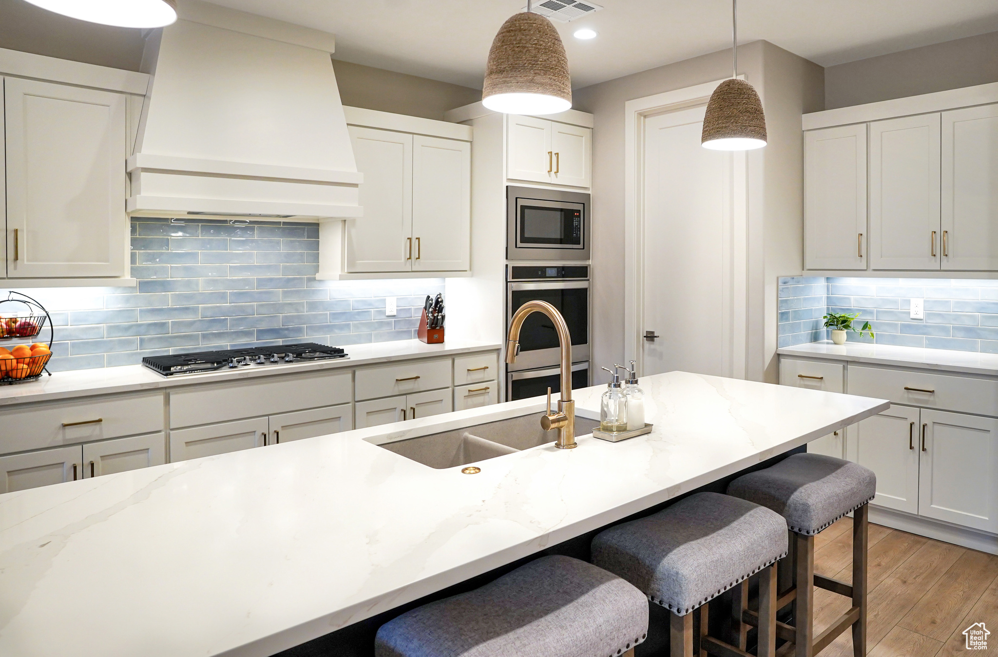 Large kitchen island with composite dual-sink and brushed 'gold' Delta Trinsic faucet.