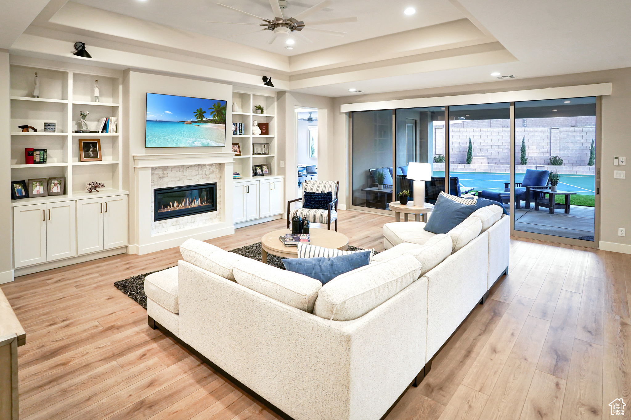 Great Room with coffered ceiling, fan, built-in shelving, and gas fireplace.