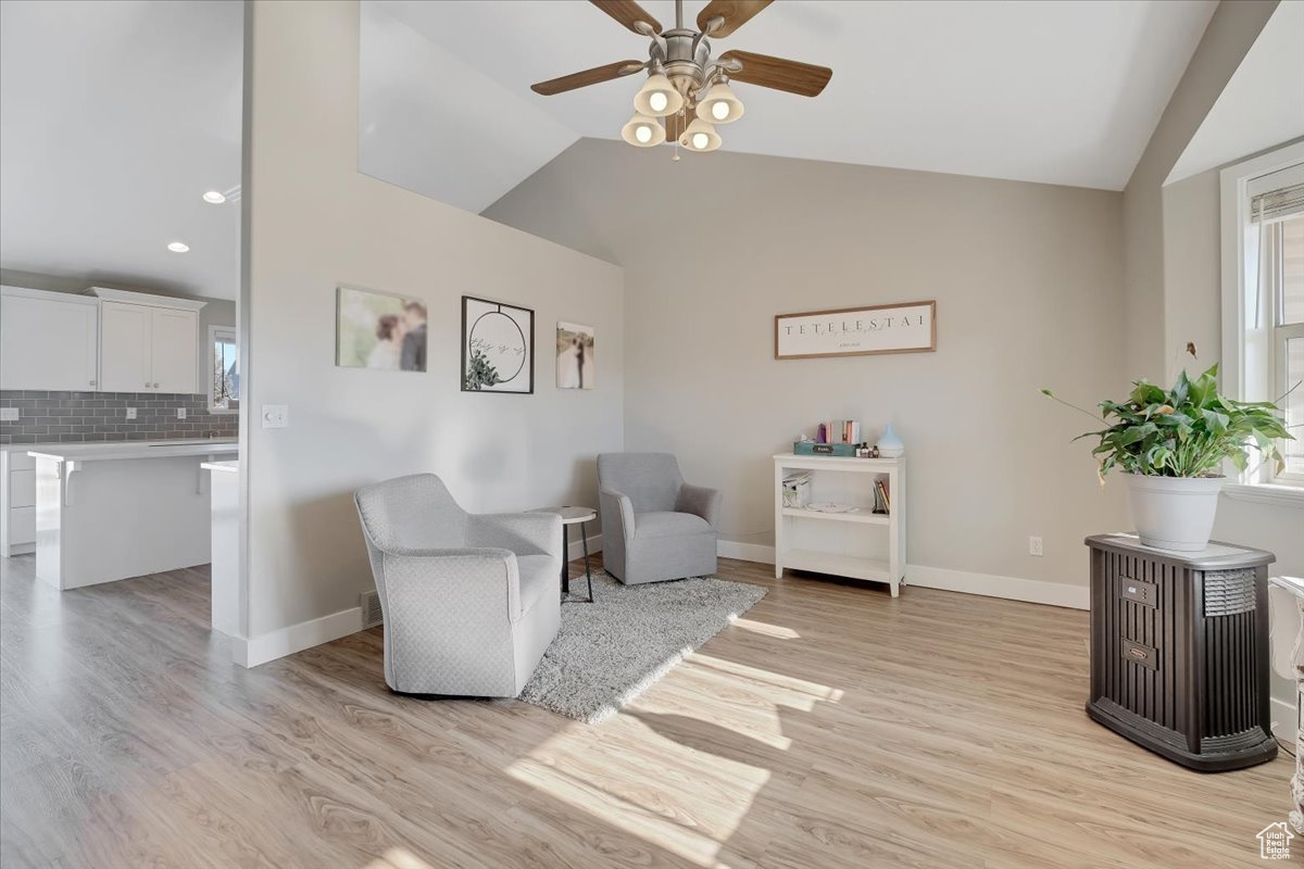 Living area with ceiling fan, light wood-type flooring, and vaulted ceiling