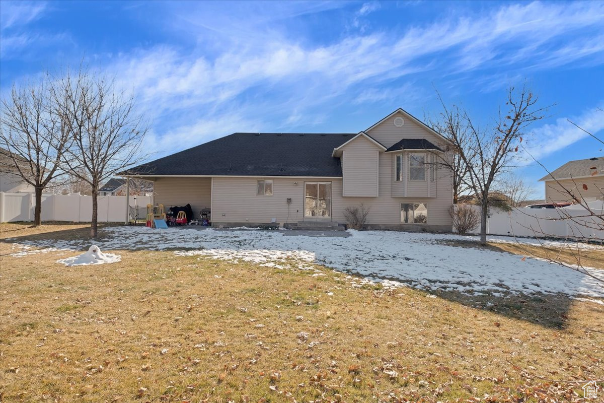 Snow covered back of property with a yard