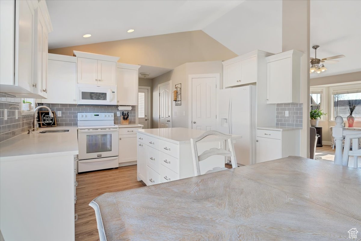 Kitchen with white cabinetry, sink, white appliances, and tasteful backsplash