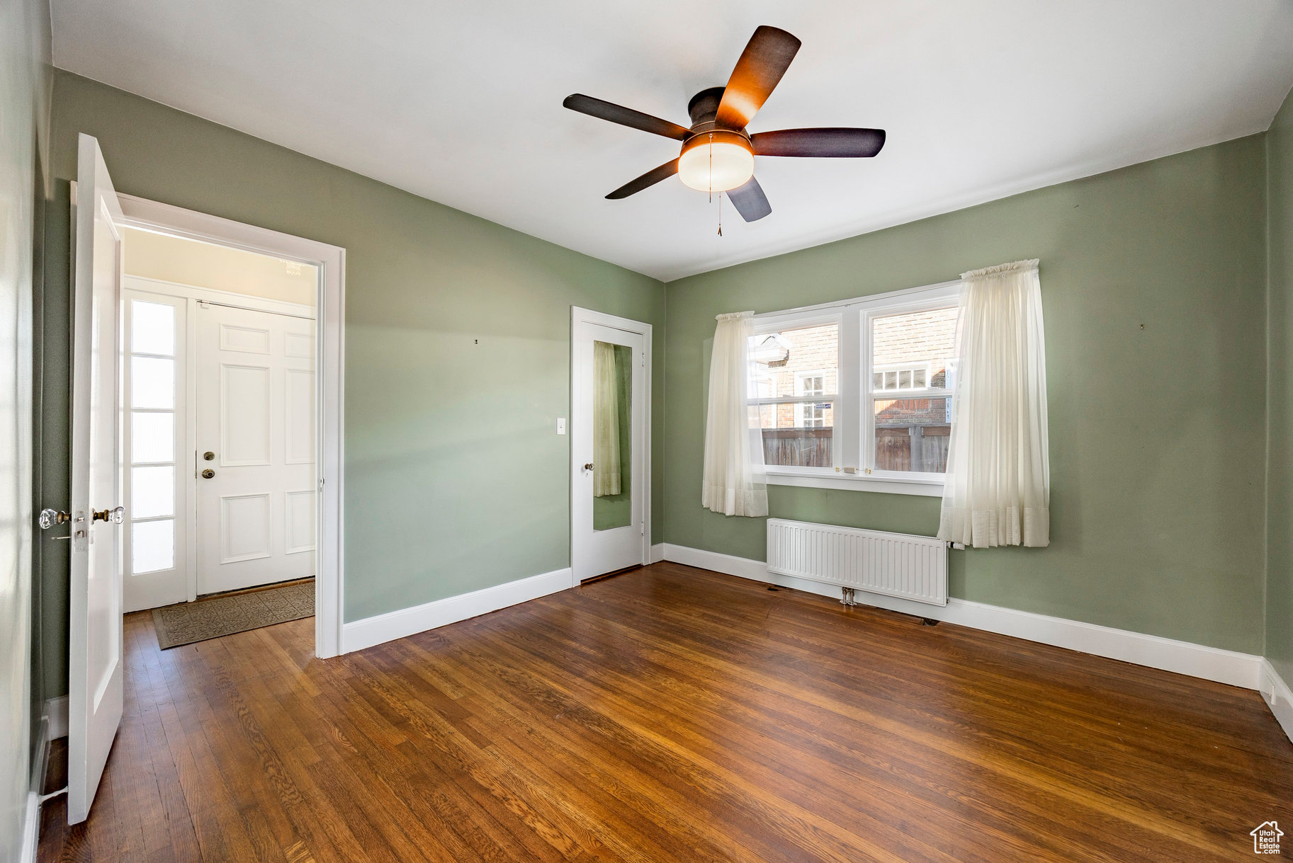 Empty room featuring radiator, ceiling fan, and dark wood-type flooring