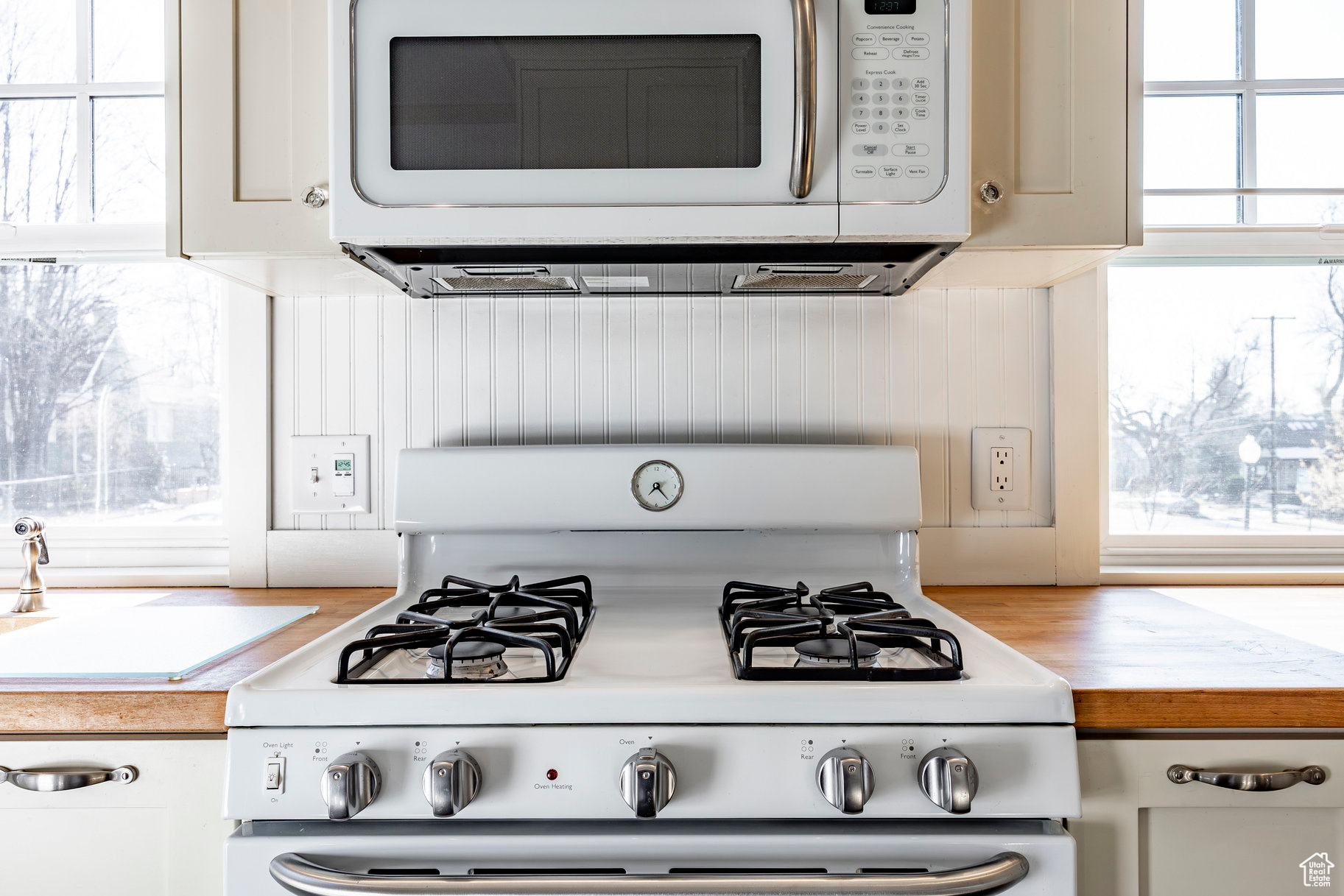 Kitchen with white cabinetry, white appliances, and a healthy amount of sunlight