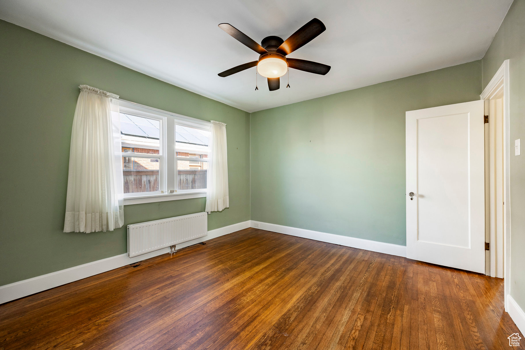 Spare room featuring radiator, dark wood-type flooring, and ceiling fan