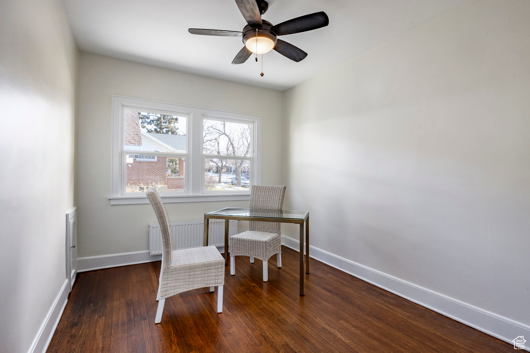 Office with ceiling fan, dark hardwood / wood-style floors, and radiator heating unit