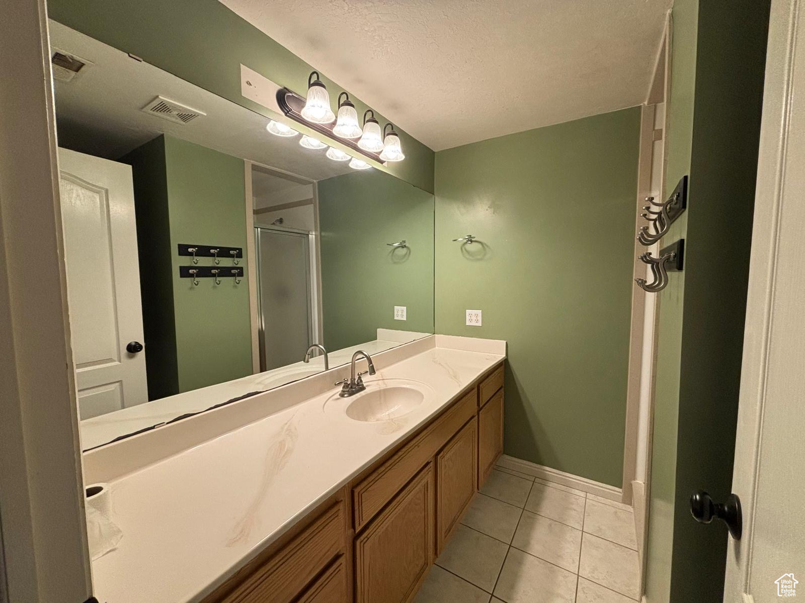 Bathroom featuring vanity, a textured ceiling, tile patterned floors, and a shower with door