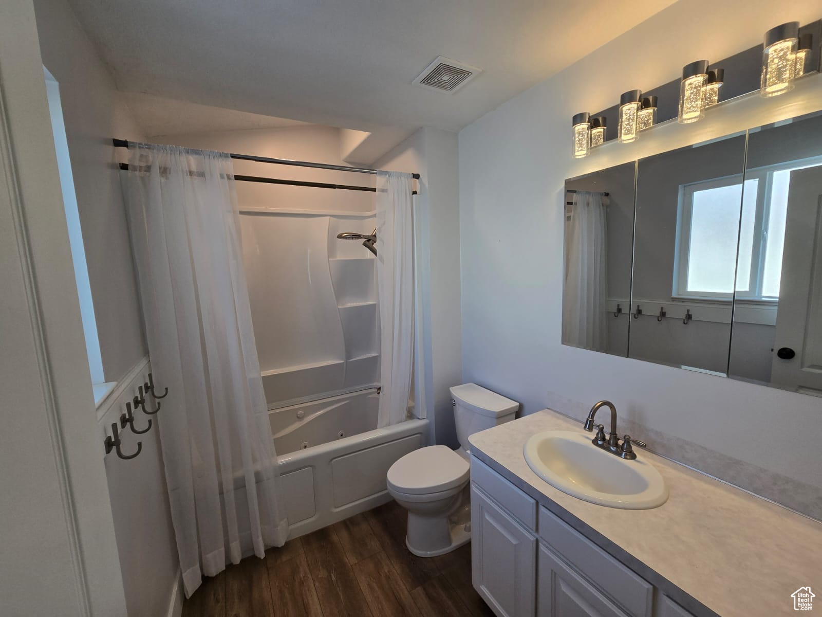 Full bathroom featuring toilet, vanity, wood-type flooring, and shower / bathtub combination with curtain