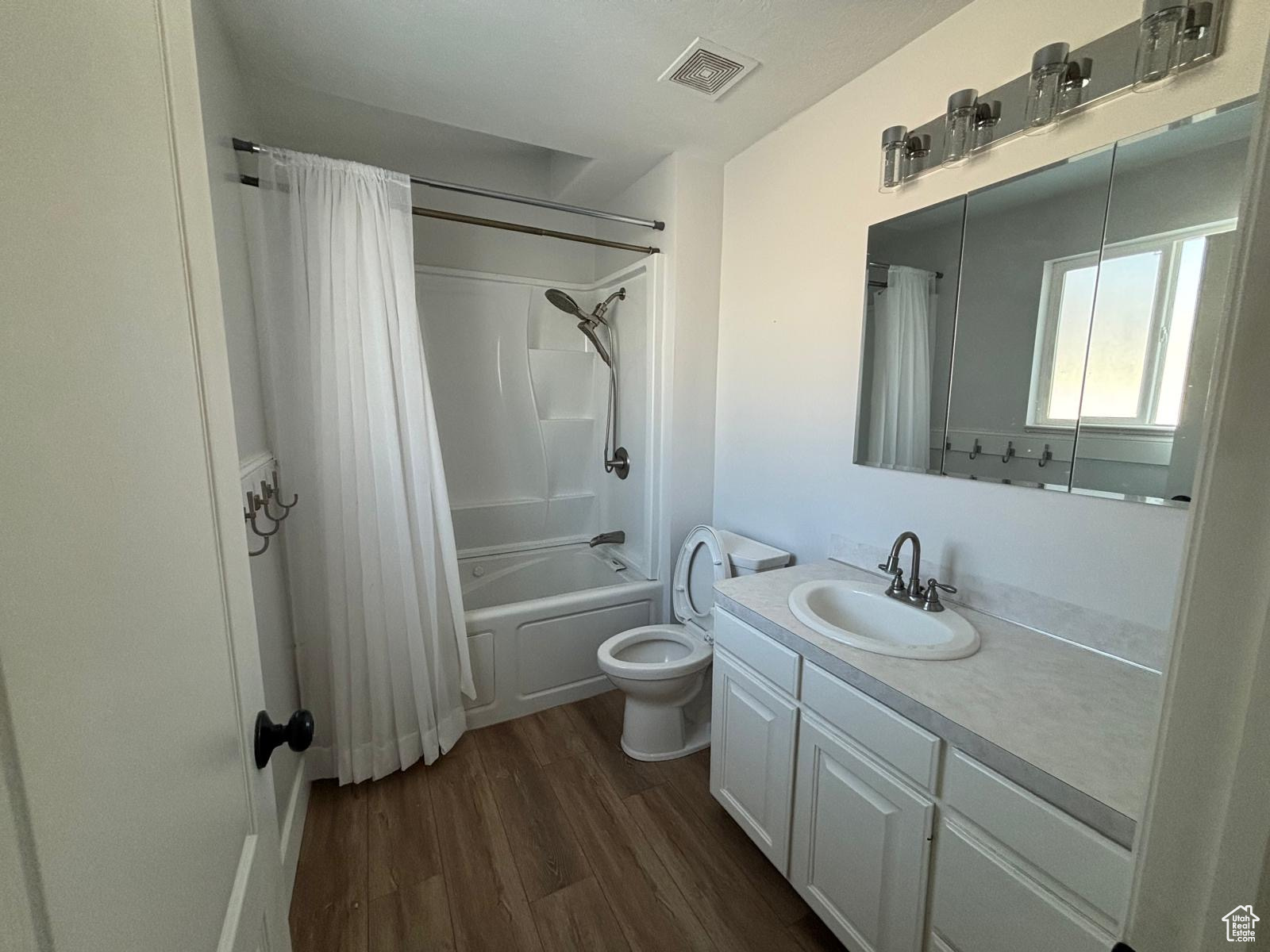 Full bathroom featuring hardwood / wood-style flooring, toilet, vanity, and shower / tub combo