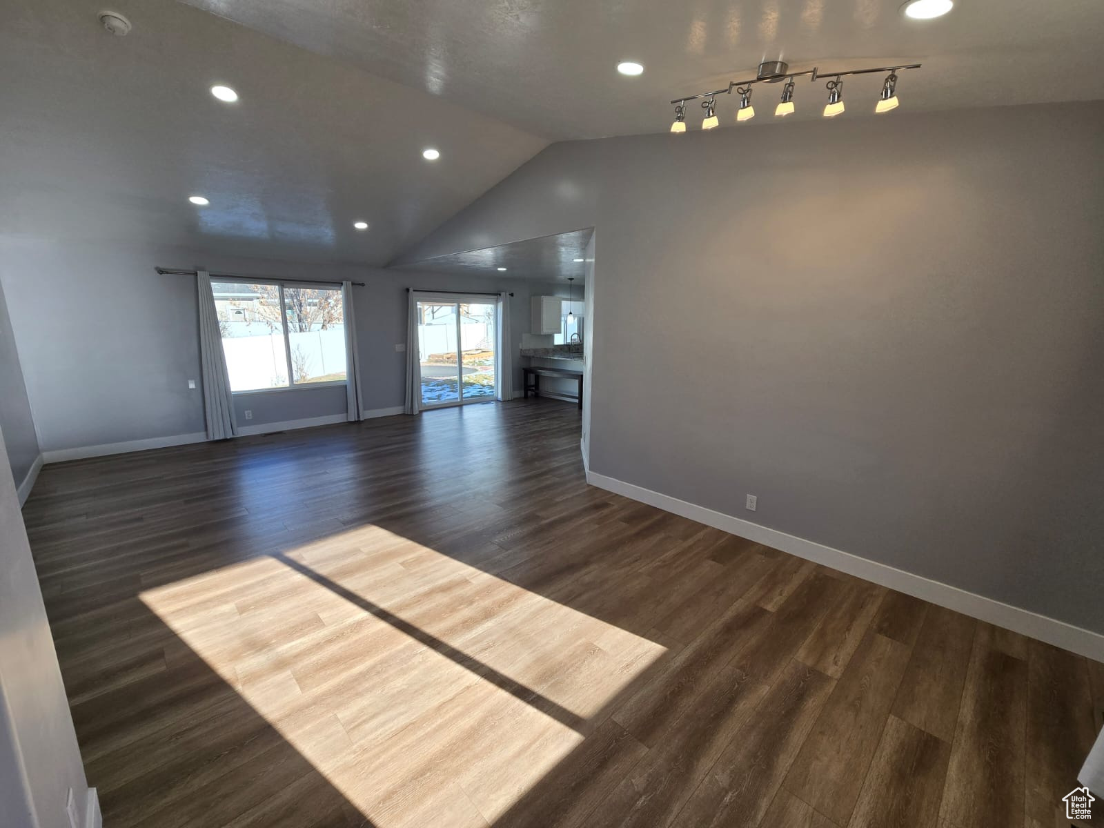 Spare room featuring vaulted ceiling and dark wood-type flooring