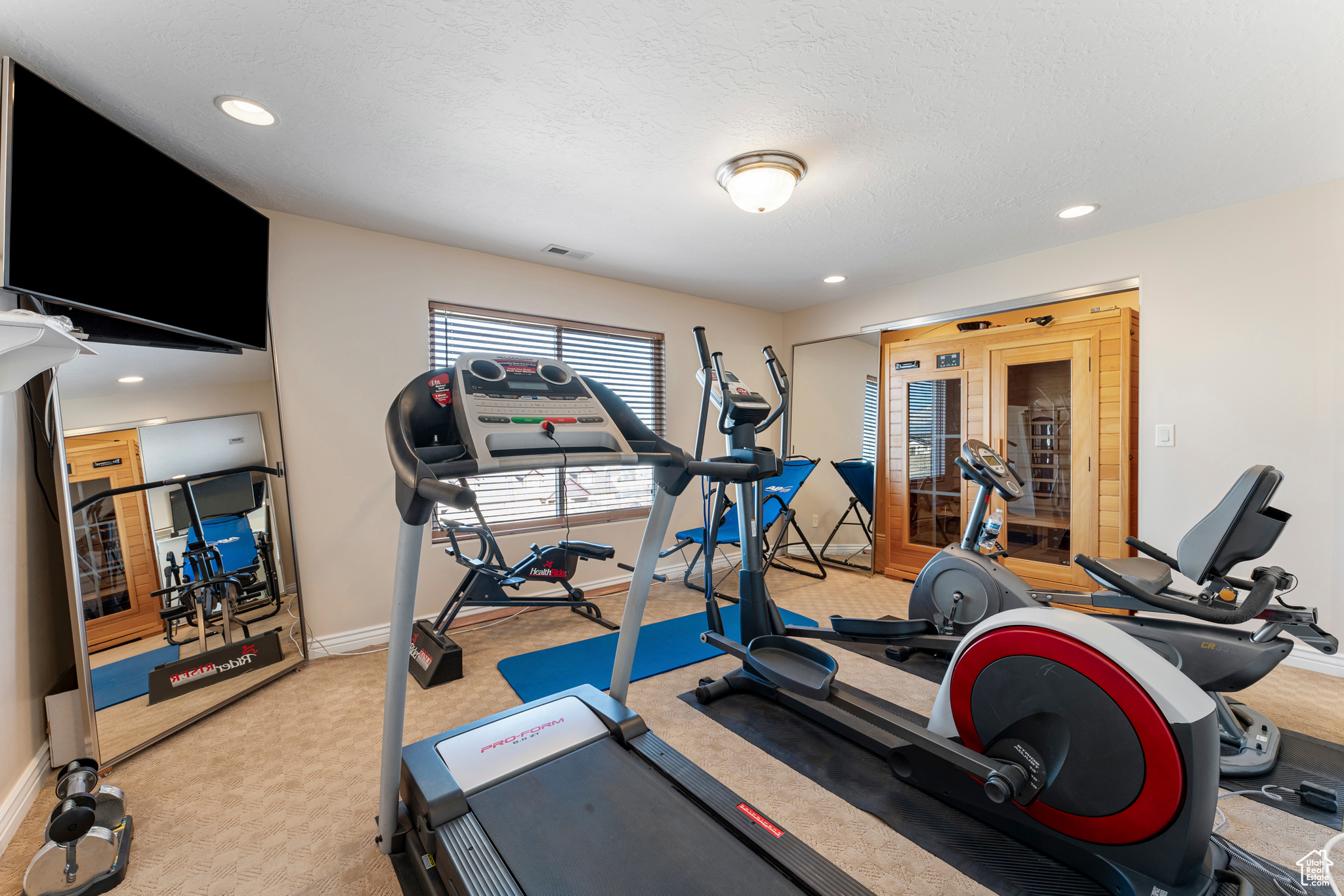 Workout room with light carpet and a textured ceiling