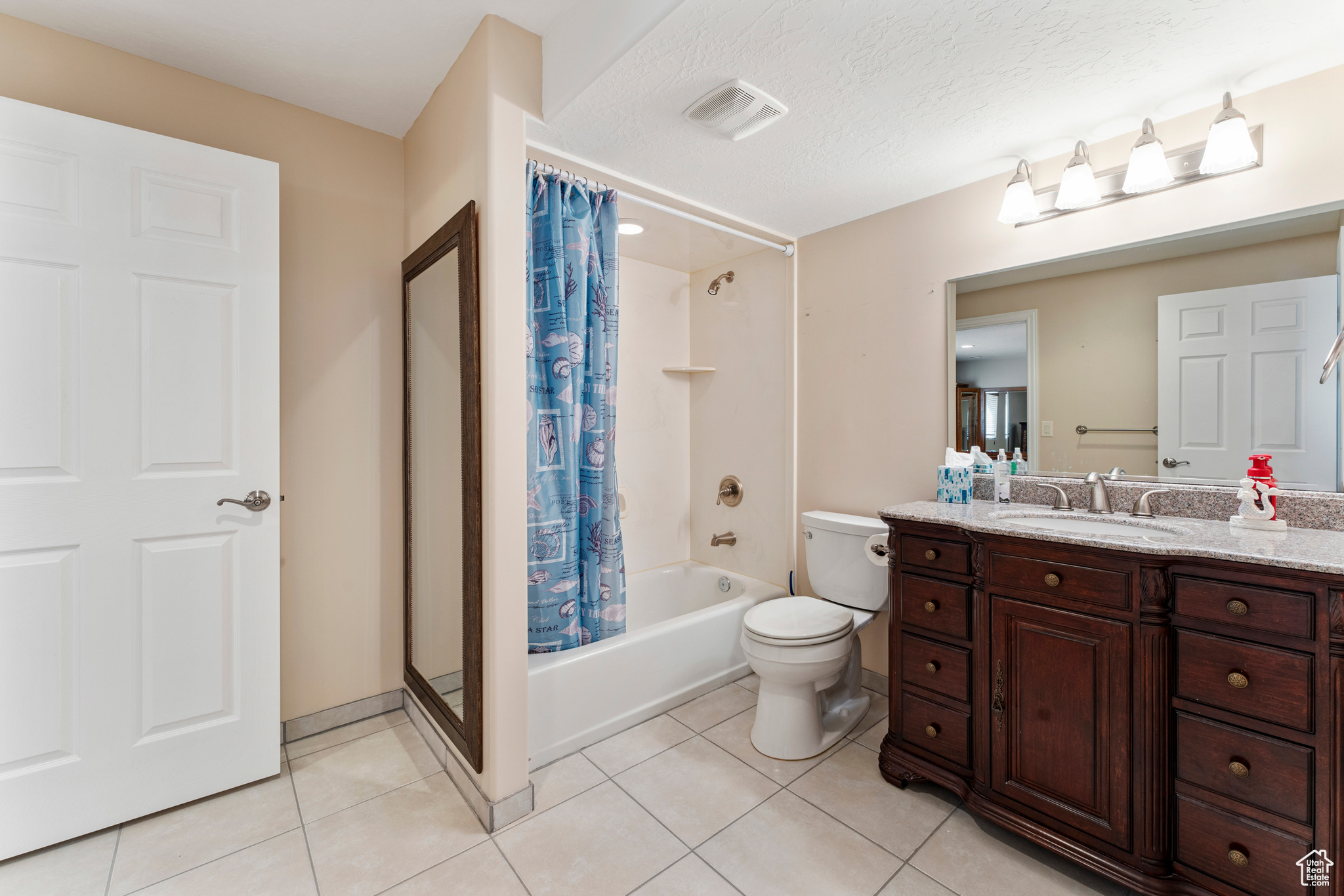 Full bathroom featuring vanity, shower / tub combo, toilet, tile patterned floors, and a textured ceiling