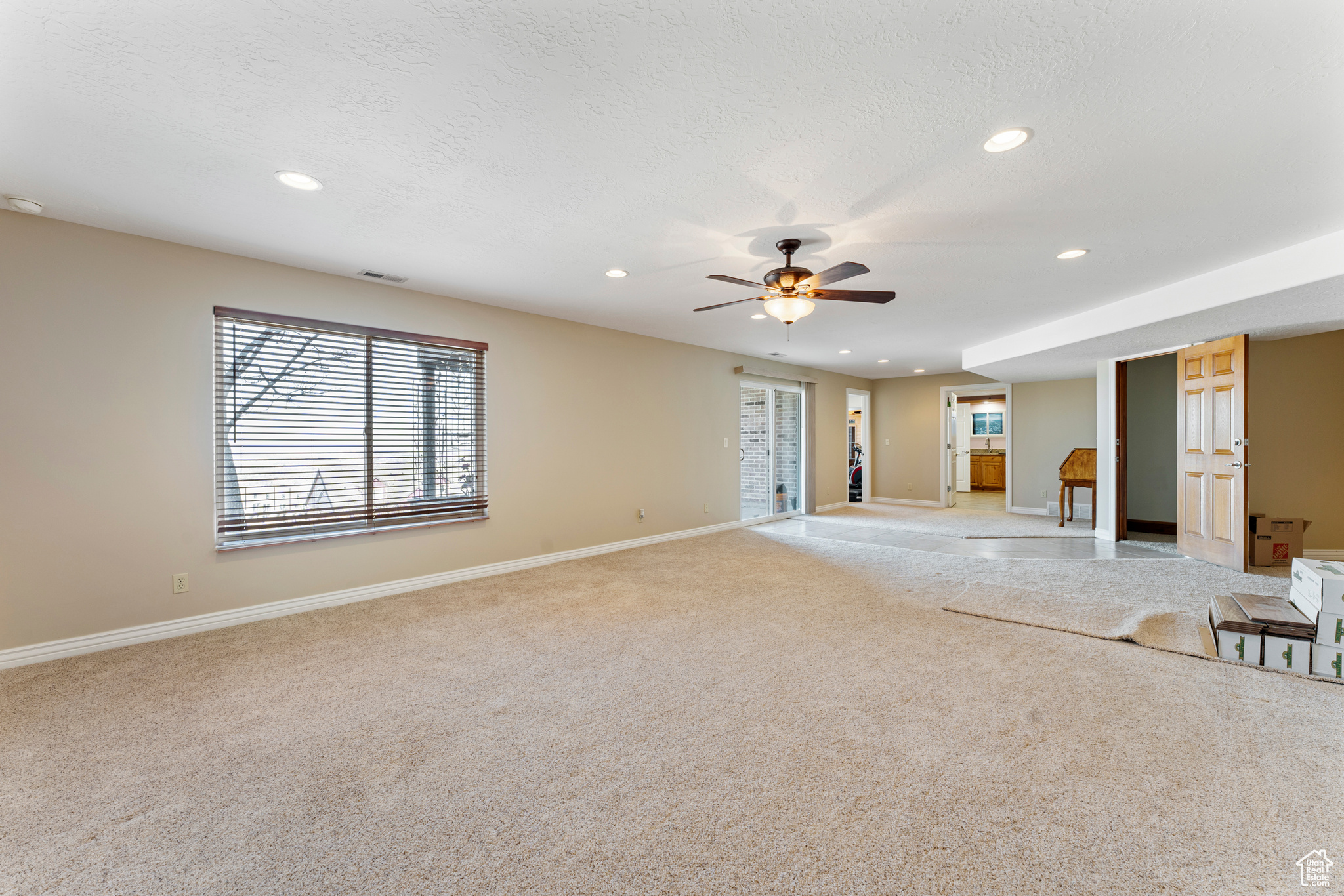 Unfurnished living room featuring ceiling fan, light carpet, and a textured ceiling