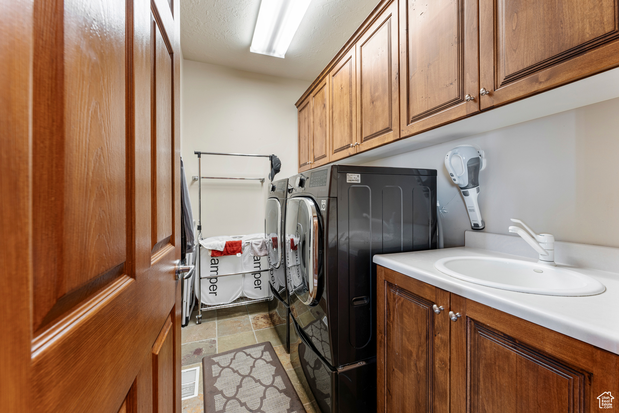 Clothes washing area featuring cabinets, washing machine and clothes dryer, and sink