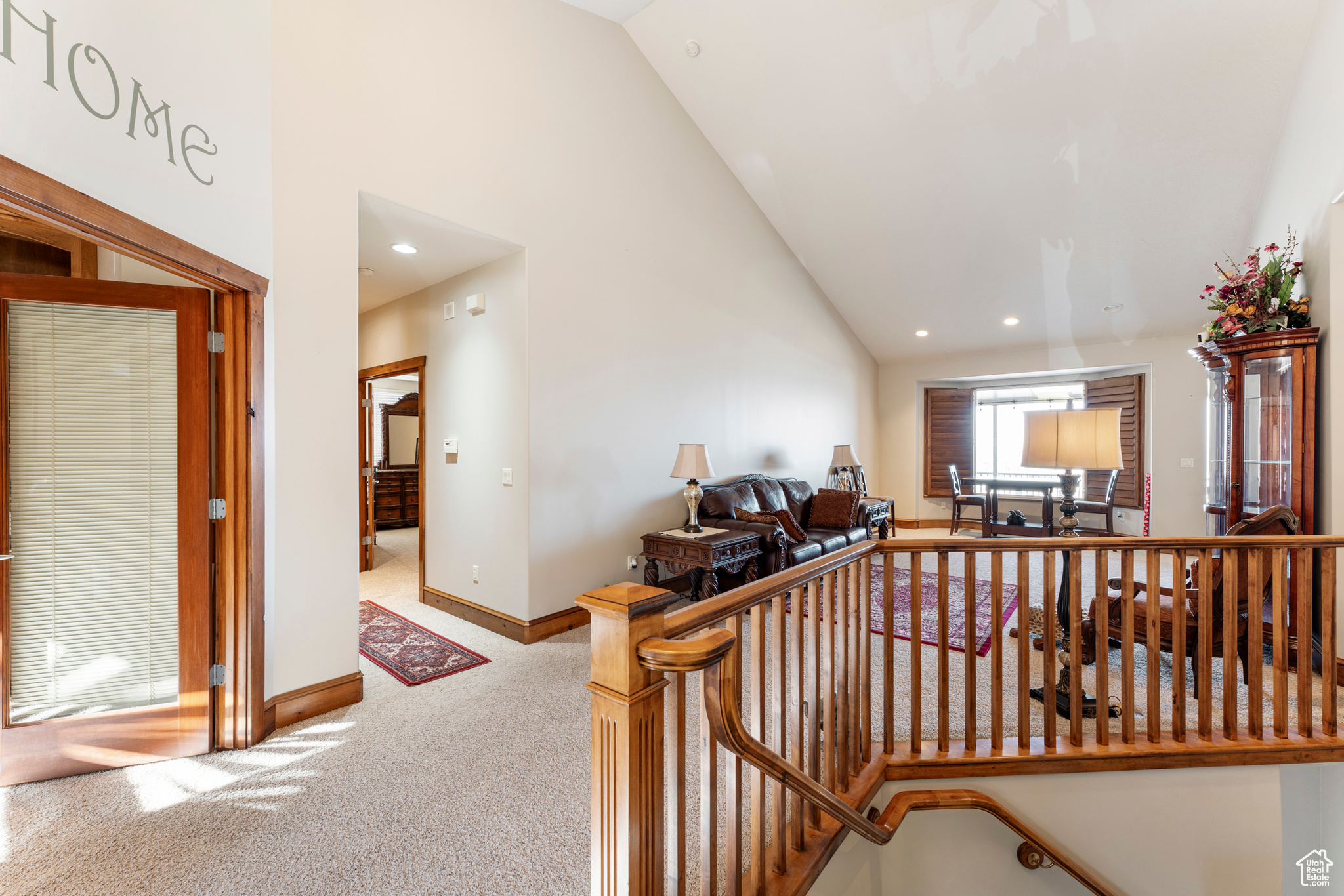 Hallway featuring carpet flooring and high vaulted ceiling