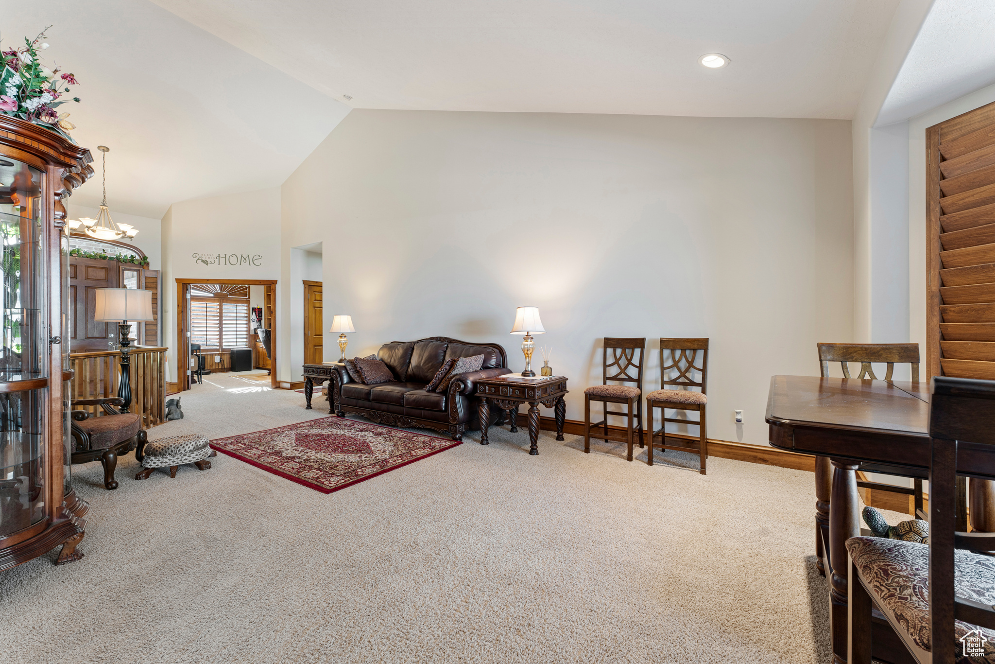 Carpeted living room featuring lofted ceiling and a notable chandelier