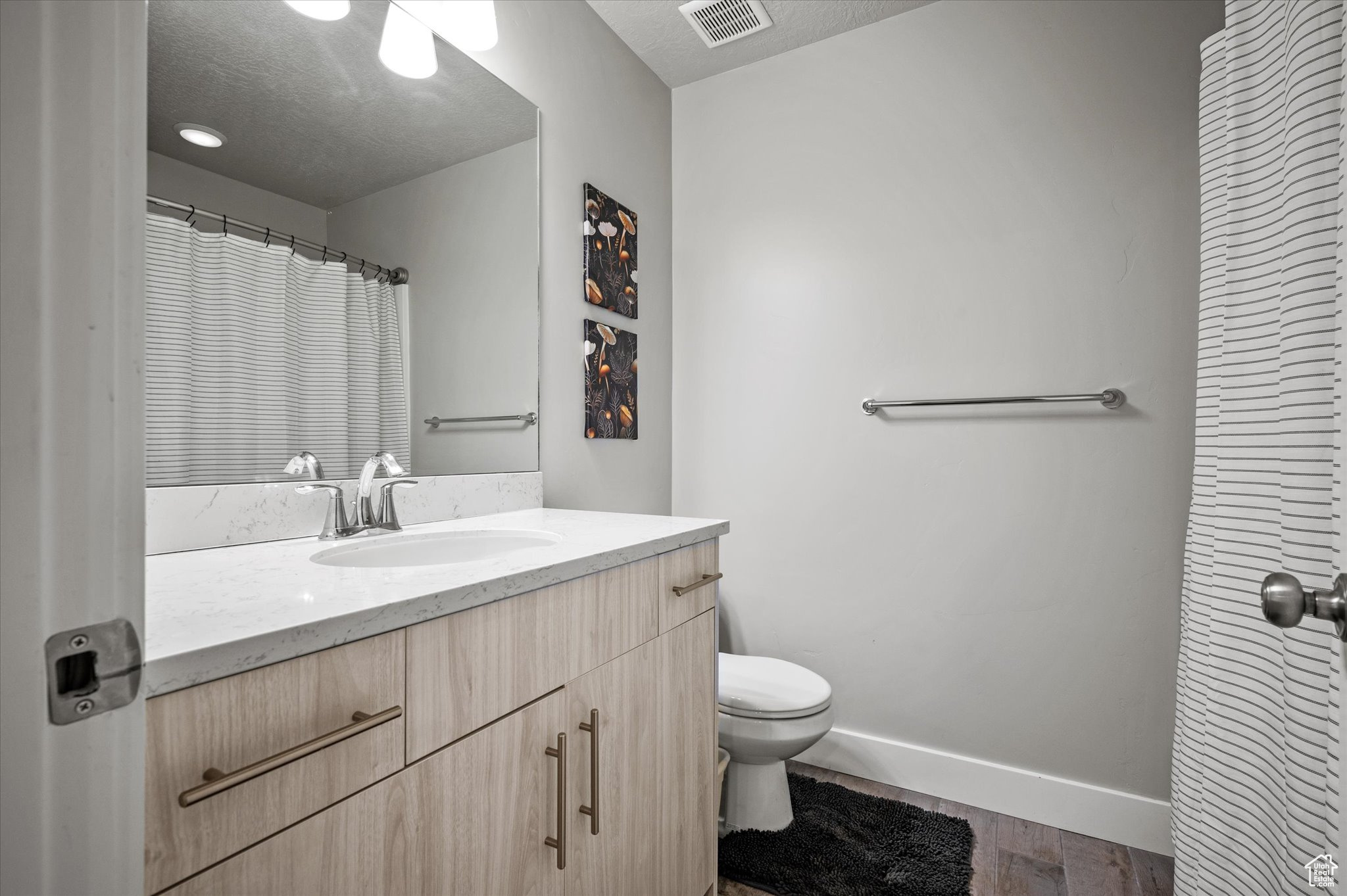 Bathroom with toilet, a textured ceiling, and vanity