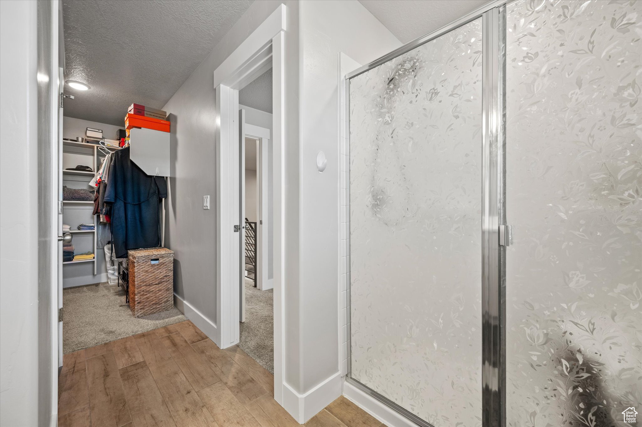 Bathroom with a shower with door, a textured ceiling, and hardwood / wood-style flooring