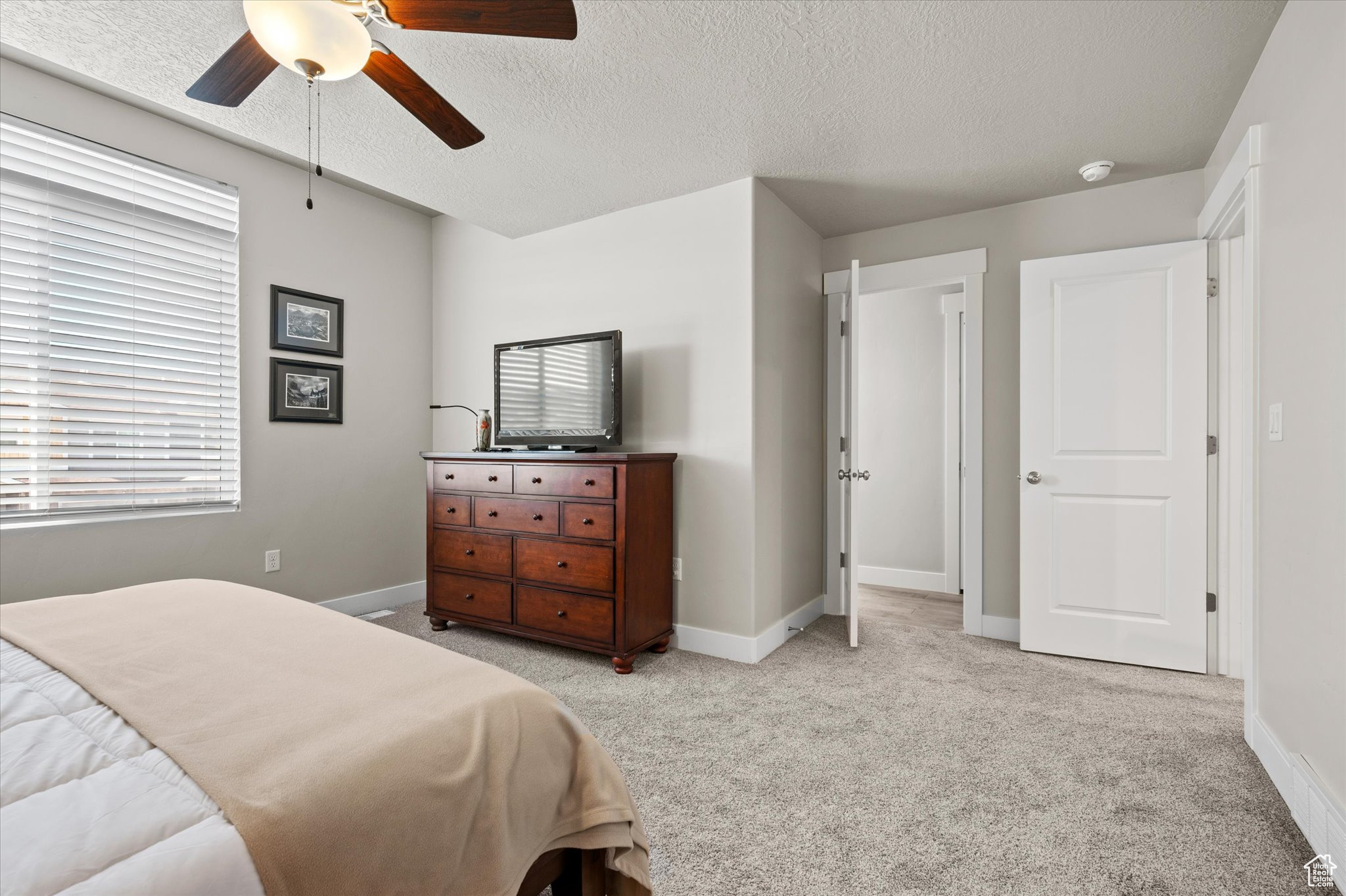 Carpeted bedroom with ceiling fan and a textured ceiling