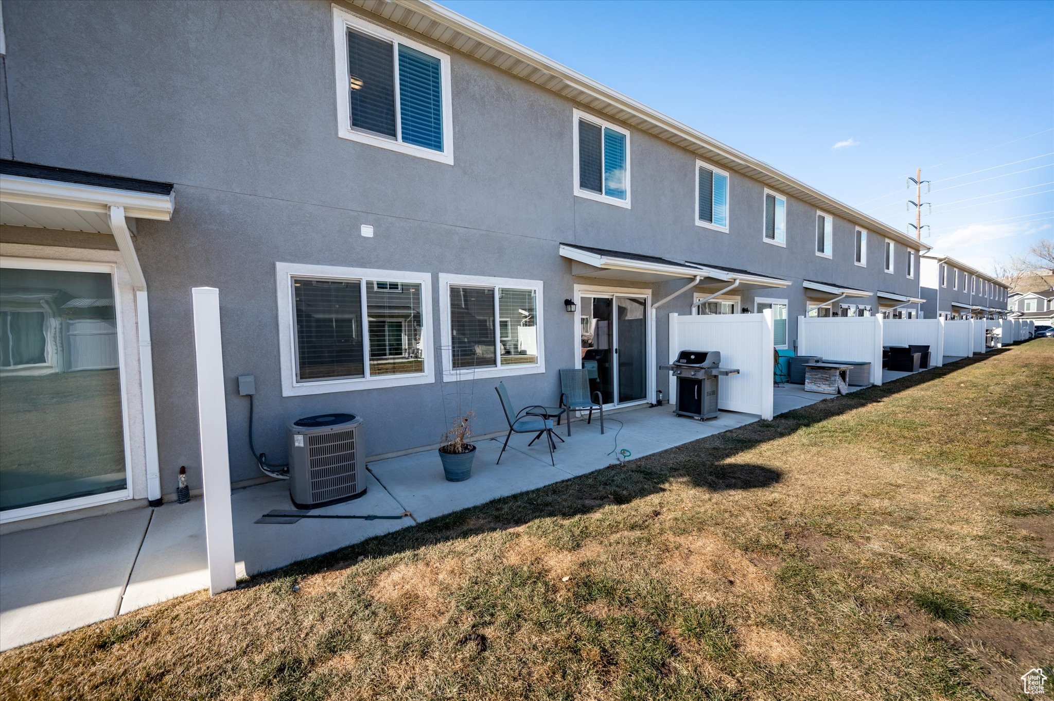 Rear view of house featuring a lawn, central AC unit, and a patio area