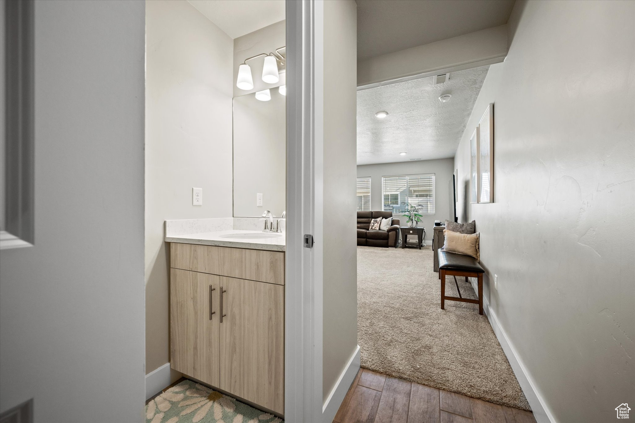 Bathroom with a textured ceiling, wood-type flooring, and vanity